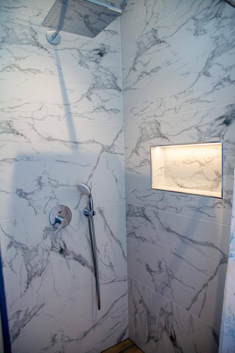 Elegante begehbare Dusche mit Marmorfliesen und Regenduschkopf.