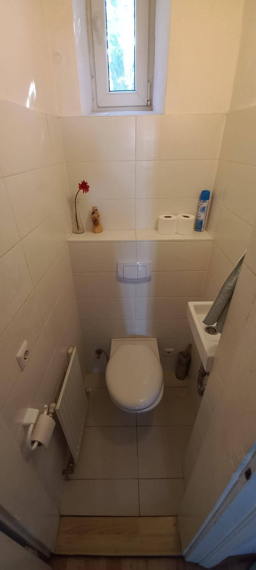Kleines Gäste-WC mit Fenster, wandmontierter Toilette und Handwaschbecken.