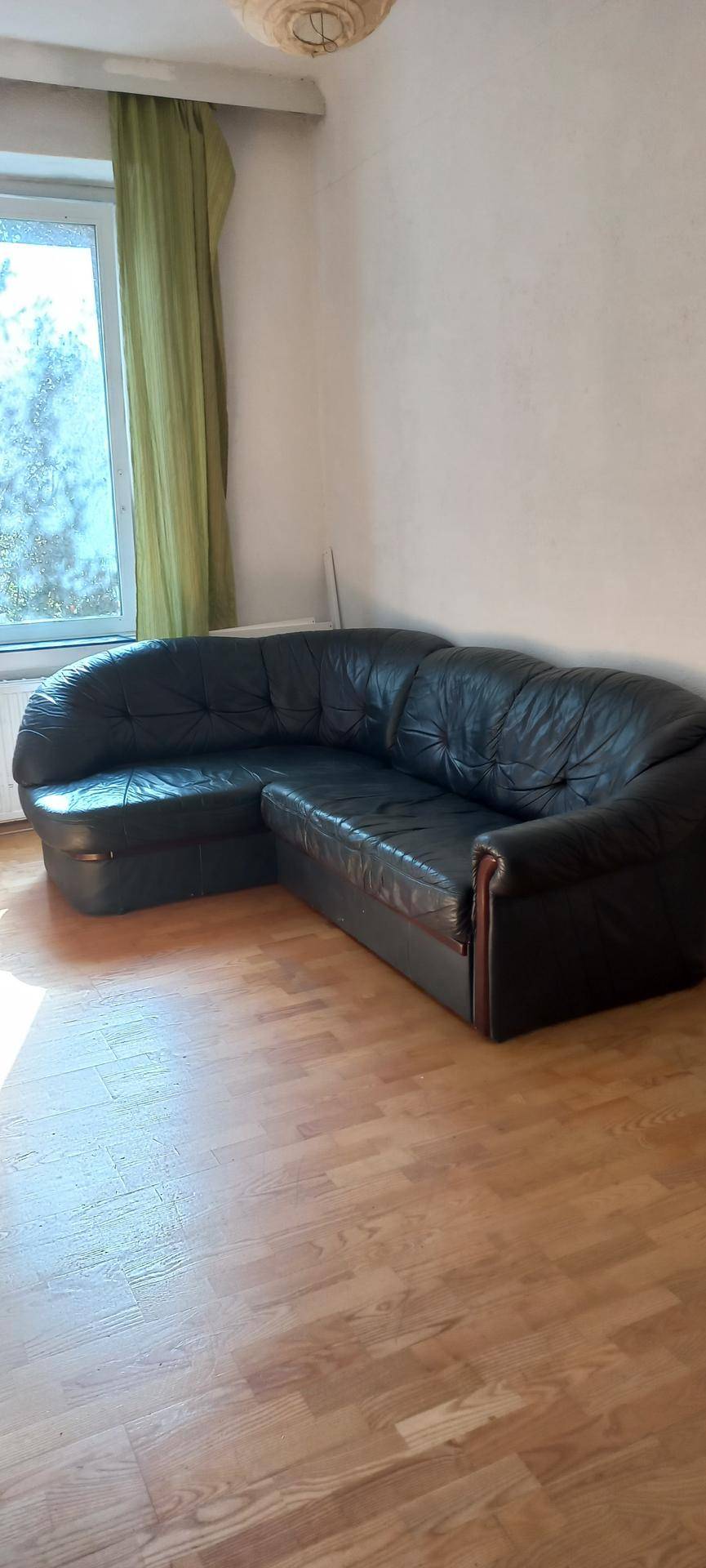 Helles Wohnzimmer mit Ledersofa und großem Fenster, das Tageslicht hereinlässt.