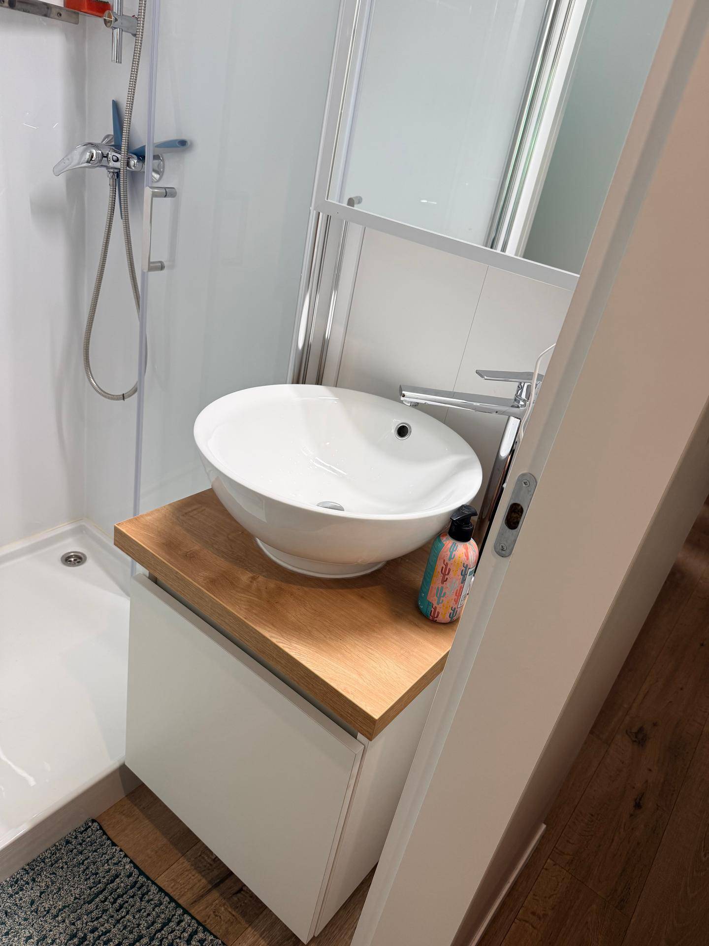 Modernes Badezimmer mit begehbarer Dusche und stilvollem Aufsatzwaschbecken auf Holzplatte.