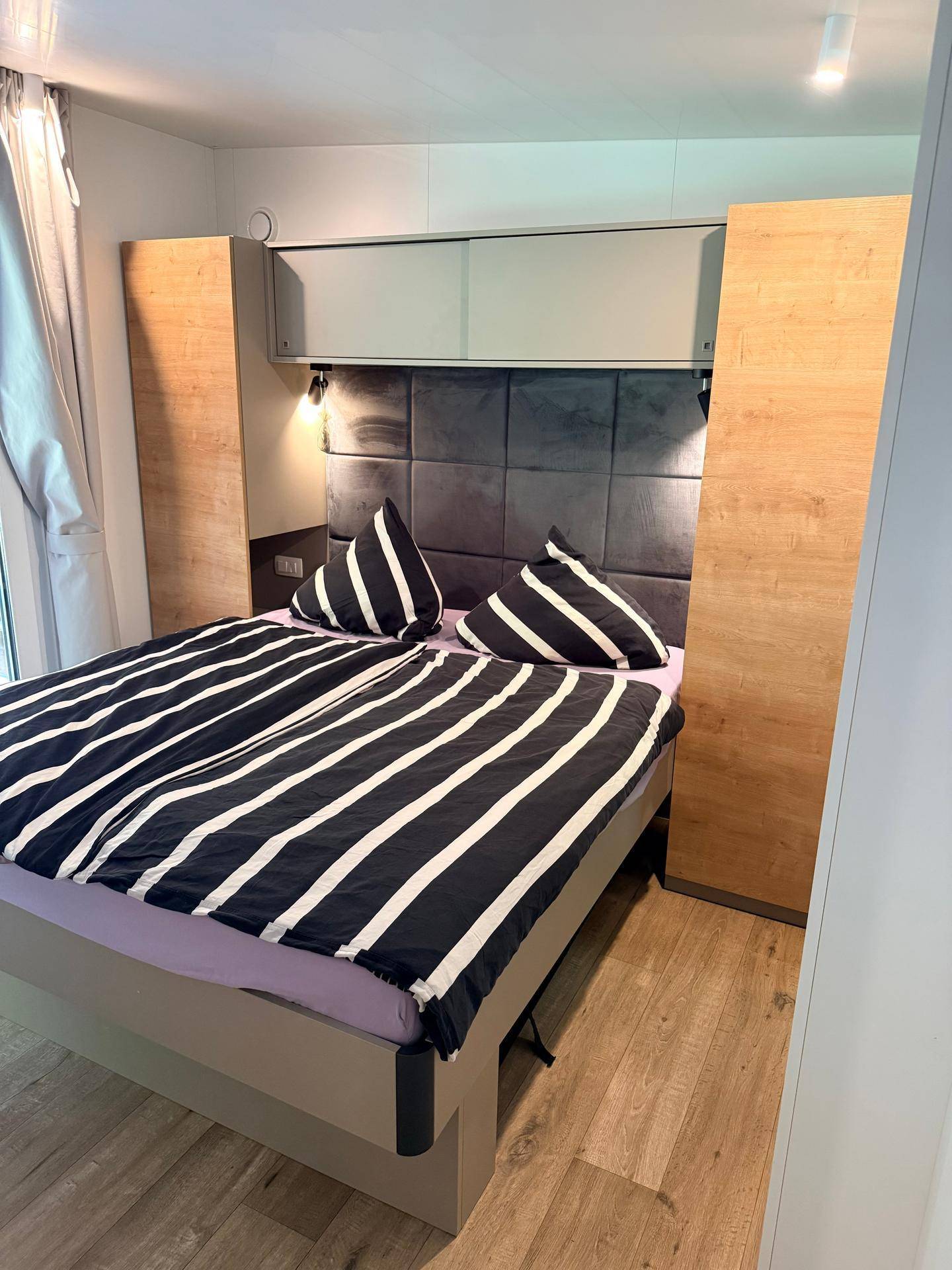 Gemütliches Schlafzimmer mit modernem Bett, integrierten Schränken und Holzelementen.