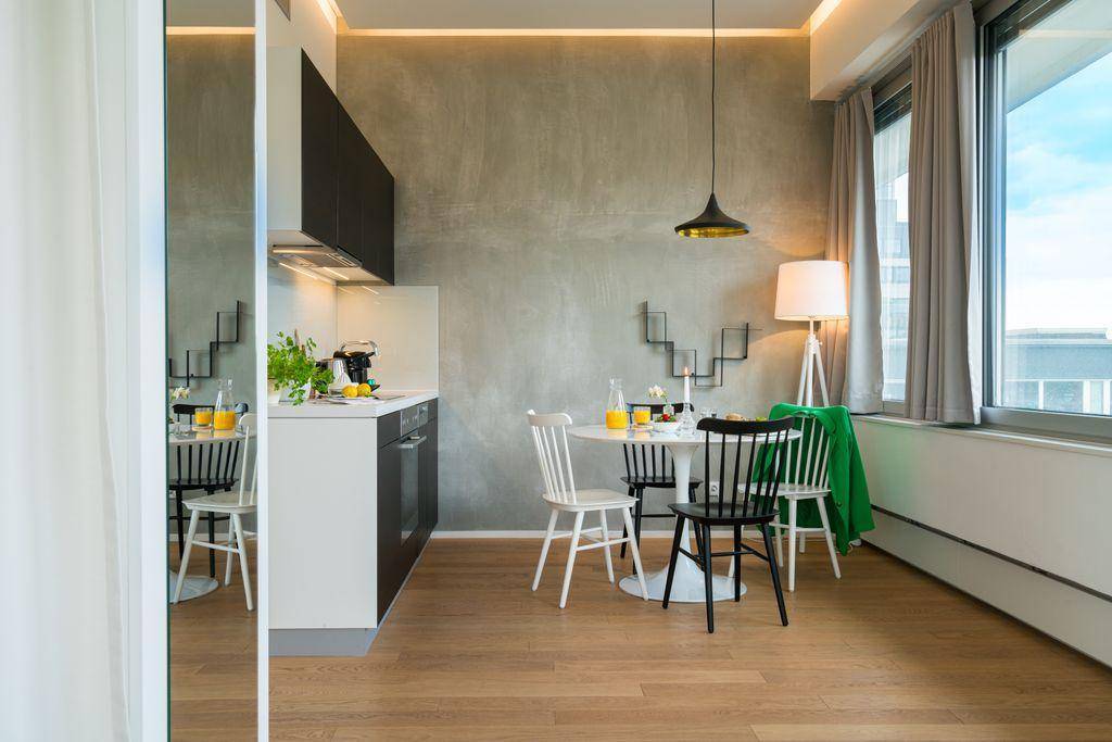 Offene Küche mit Essbereich, runden Tisch und Stühlen, ergänzt durch eine moderne Pendelleuchte.