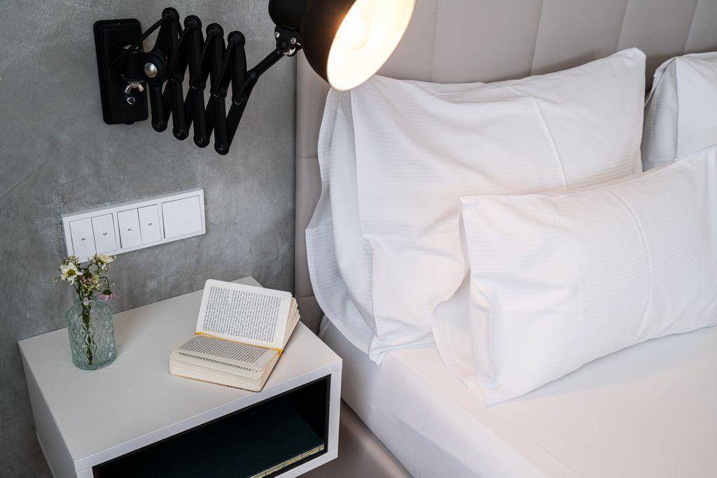 Detailansicht des Nachttisches mit Leselampe und einem Buch neben dem bequemen Bett.