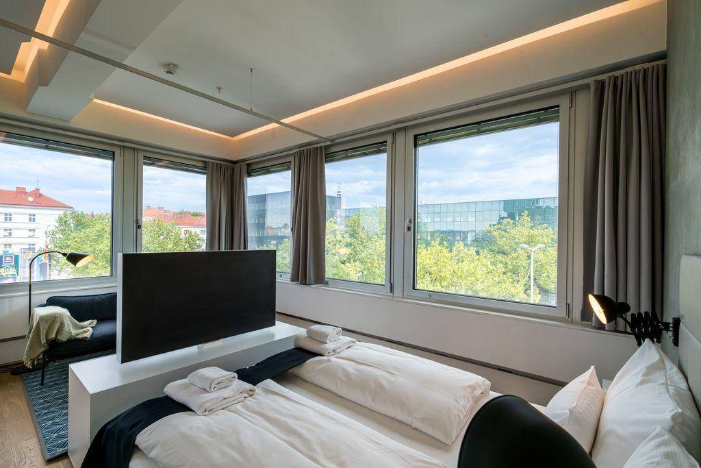 Gemütlicher Schlafbereich mit Doppelbett, Fernseher und weitem Blick durch die großen Fenster.