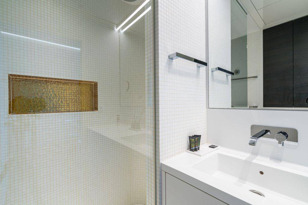 Helles Badezimmer mit moderner Dusche, integriertem Waschbecken und Spiegel.