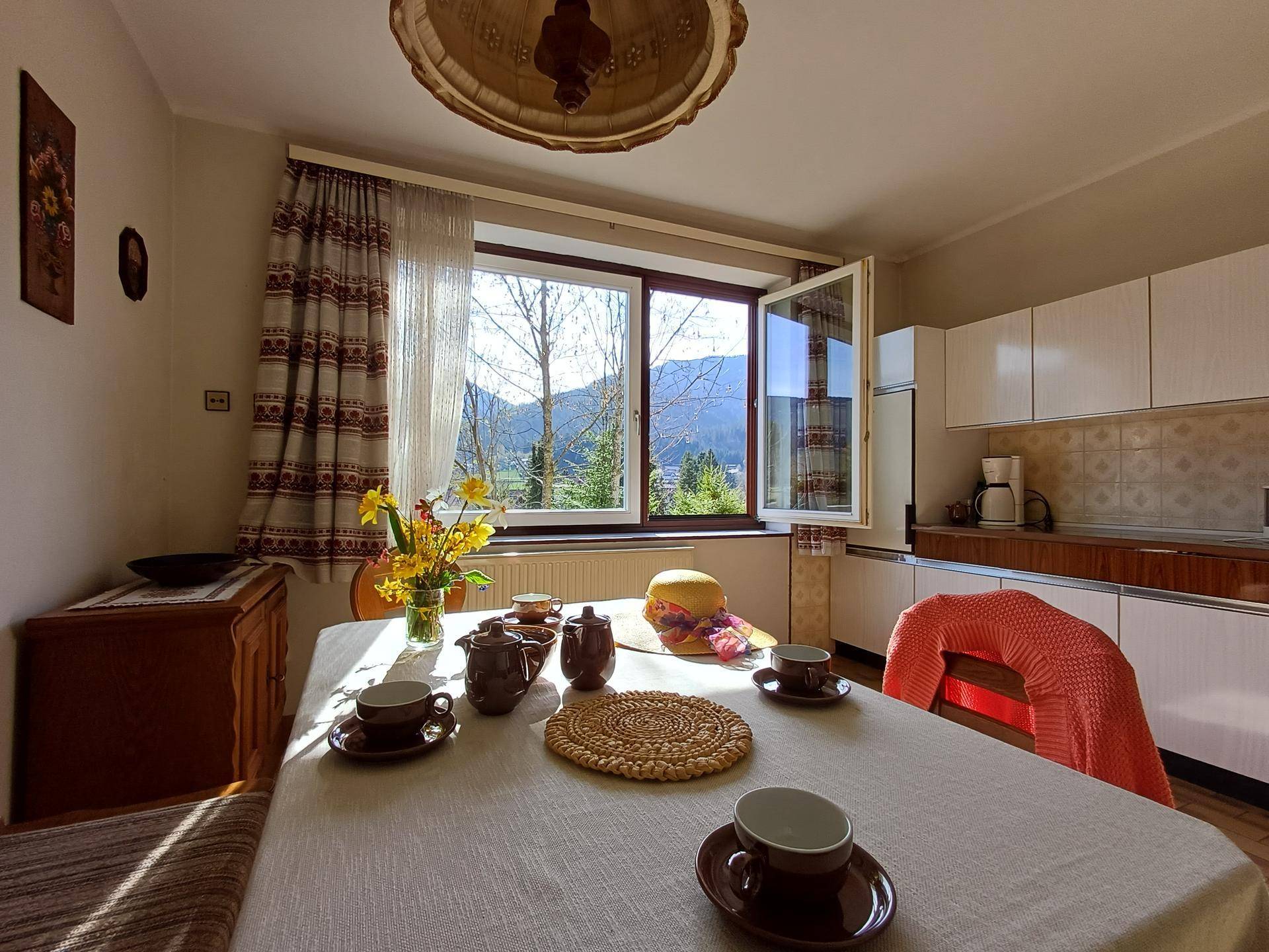Helle Küche mit Esstisch und Blick auf die Berge, ausgestattet mit traditionellen Möbeln und Fliesen.
