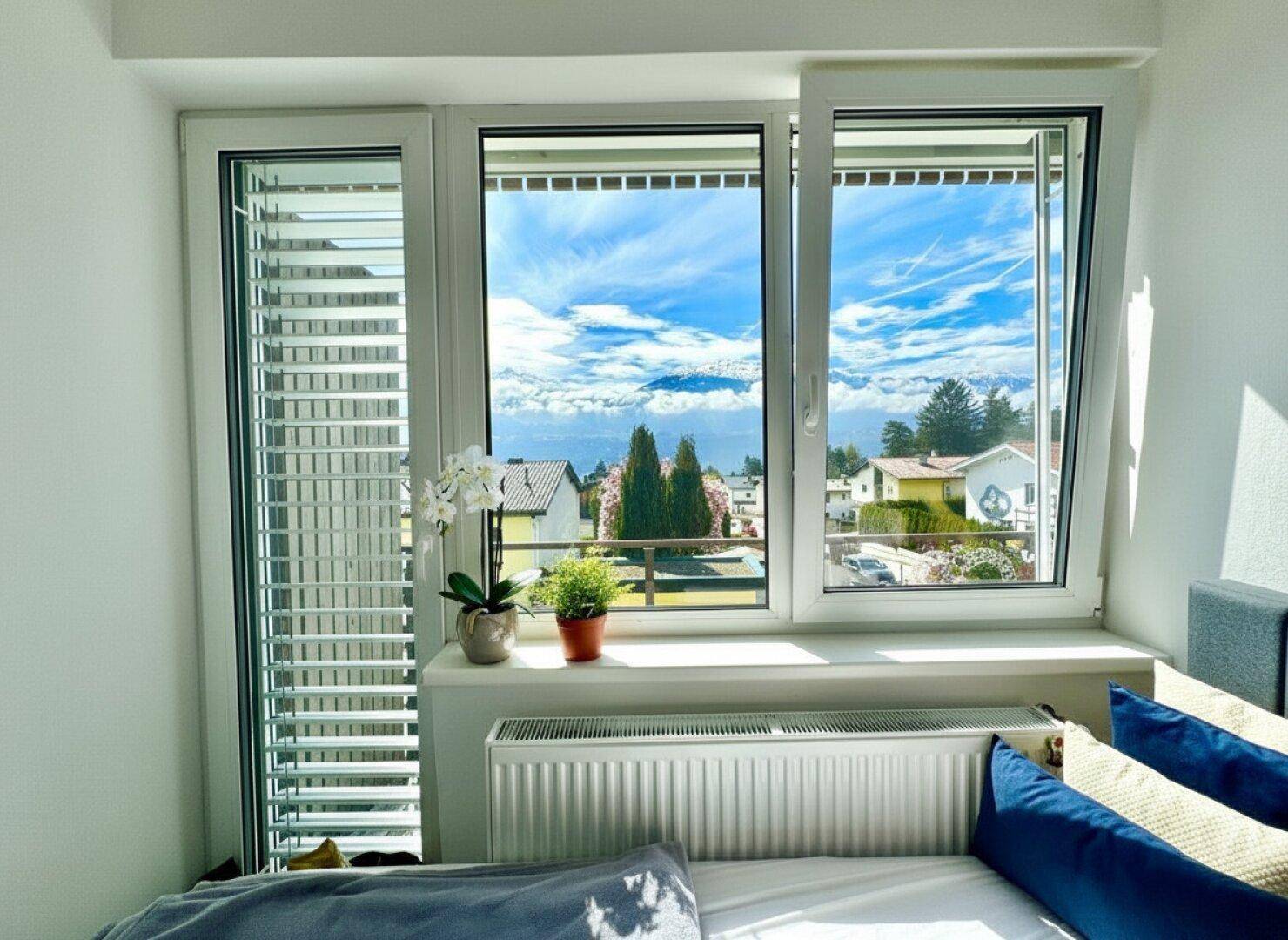 Schlafzimmer mit großem Fenster, das einen weiten Blick auf die Berge und die Umgebung bietet.