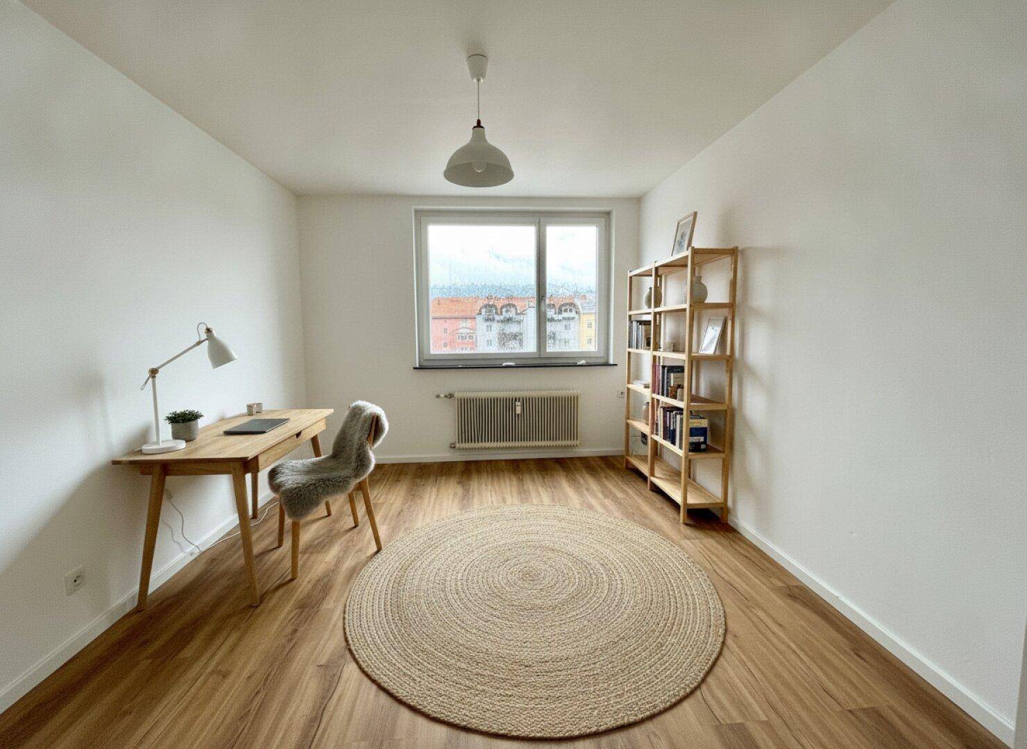 Ruhiges Arbeitszimmer mit Schreibtisch, Bücherregal und Blick auf die Stadt.