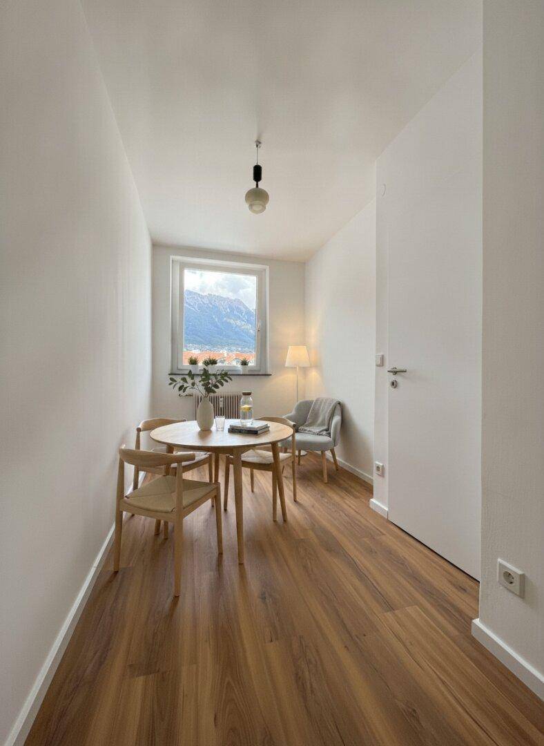 Heller Essbereich mit Holztisch, Stühlen und einem malerischen Bergblick.