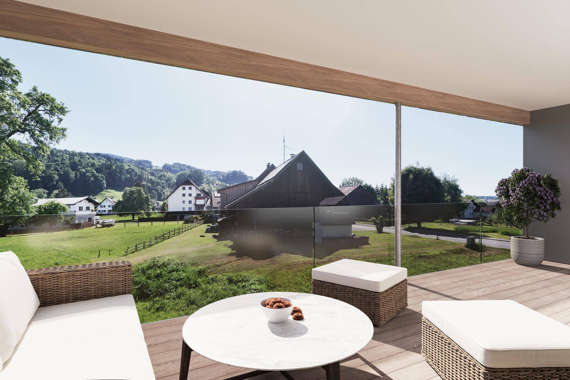 Geräumiger Balkon mit Glasgeländer und bequemen Loungemöbeln, bietet weiten Blick ins Grüne.