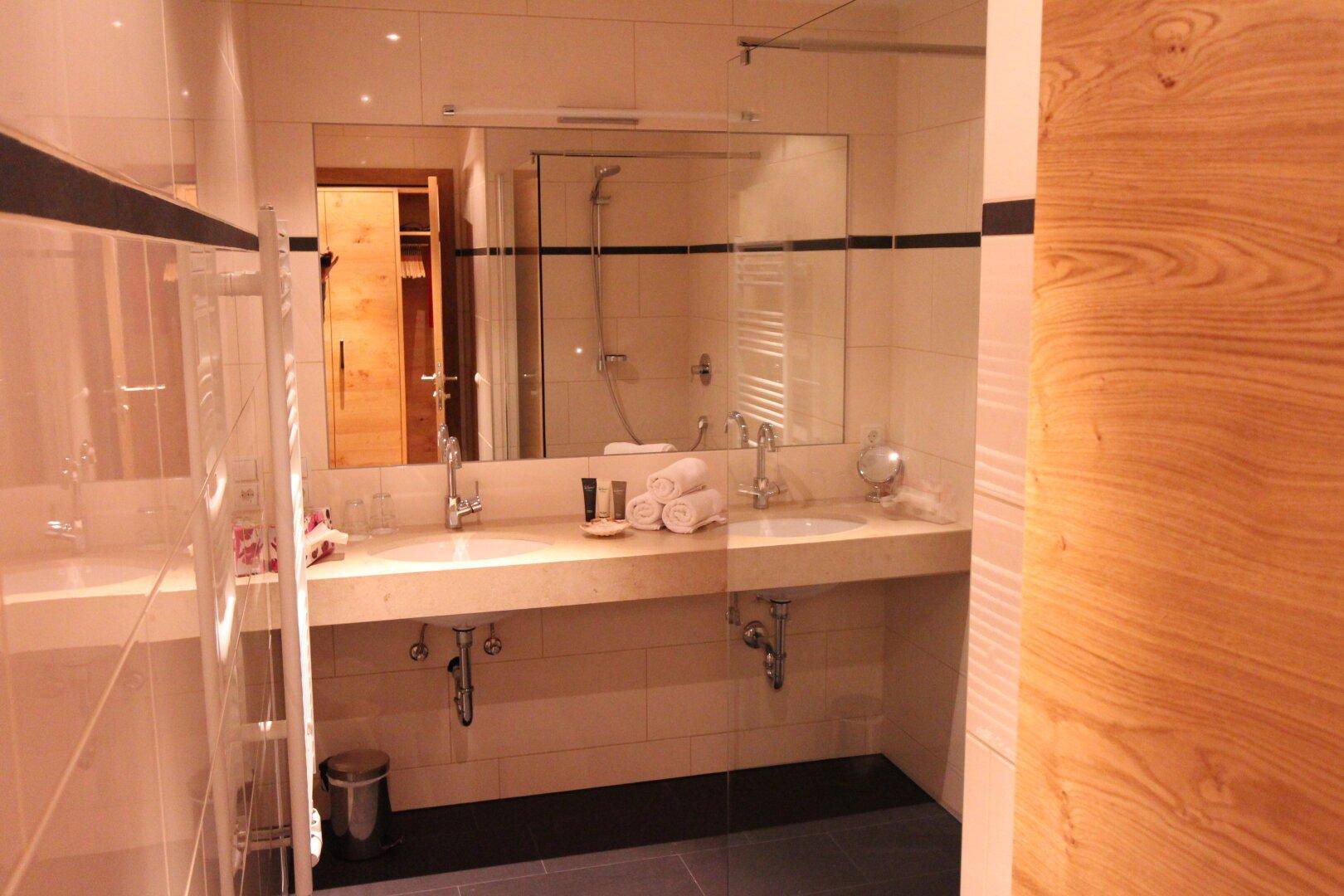 Geräumiges Badezimmer mit Doppelwaschbecken, großem Spiegel und moderner Ausstattung.