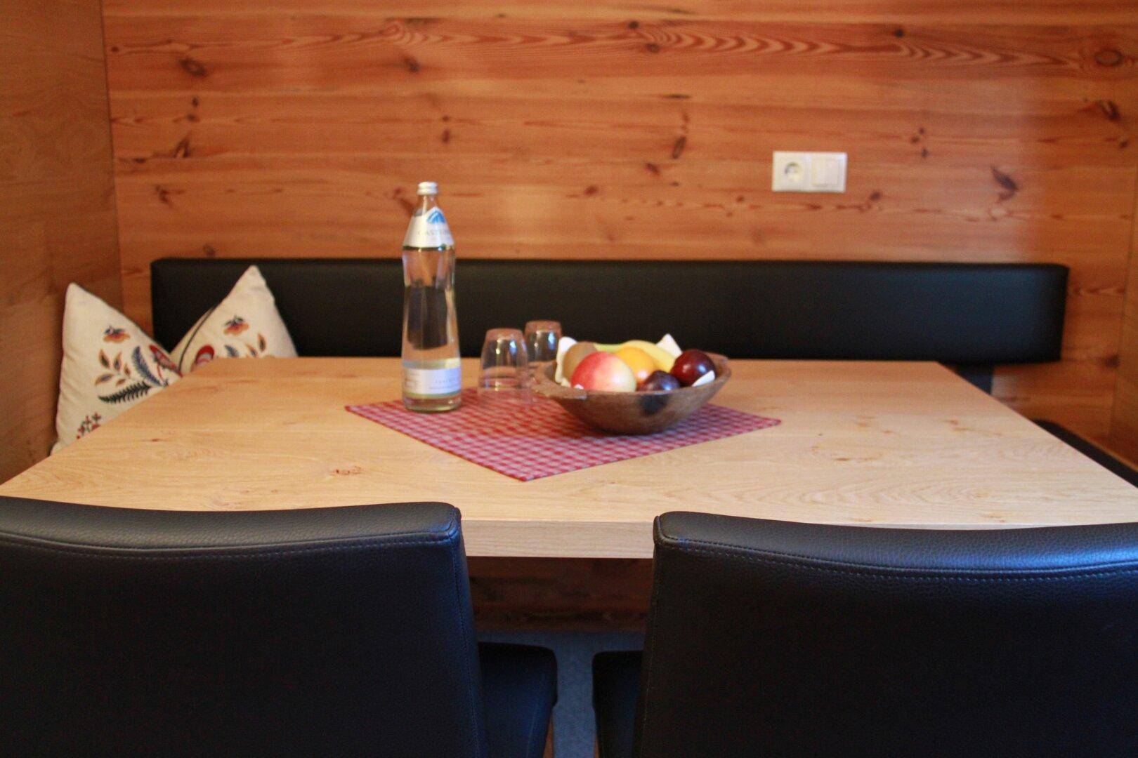 Gemütlicher Essbereich mit Holztisch, Sitzbank und schwarzen Stühlen.