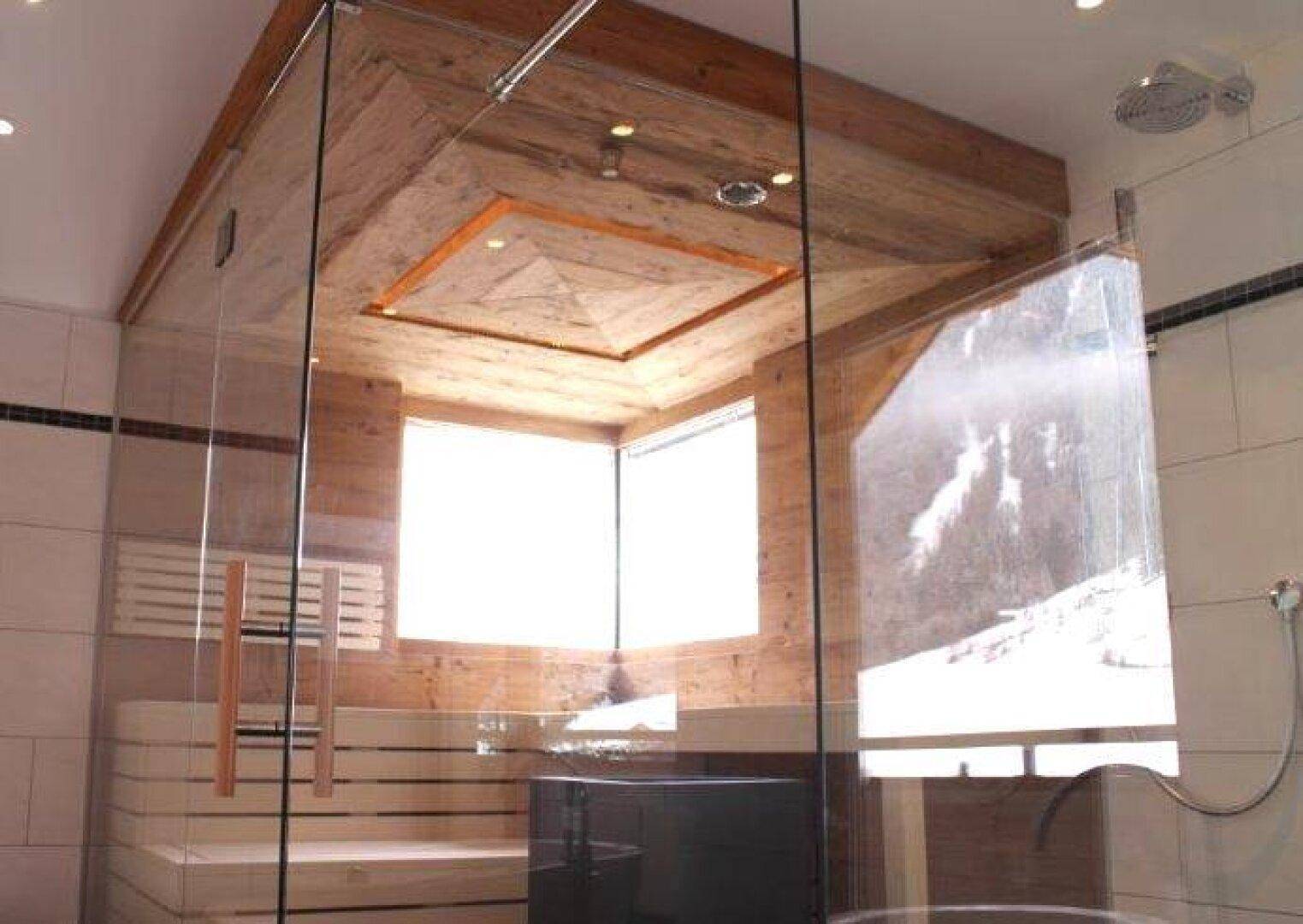 Moderne Sauna mit Holzbänken und Glaswänden, integriert in ein Badezimmer.
