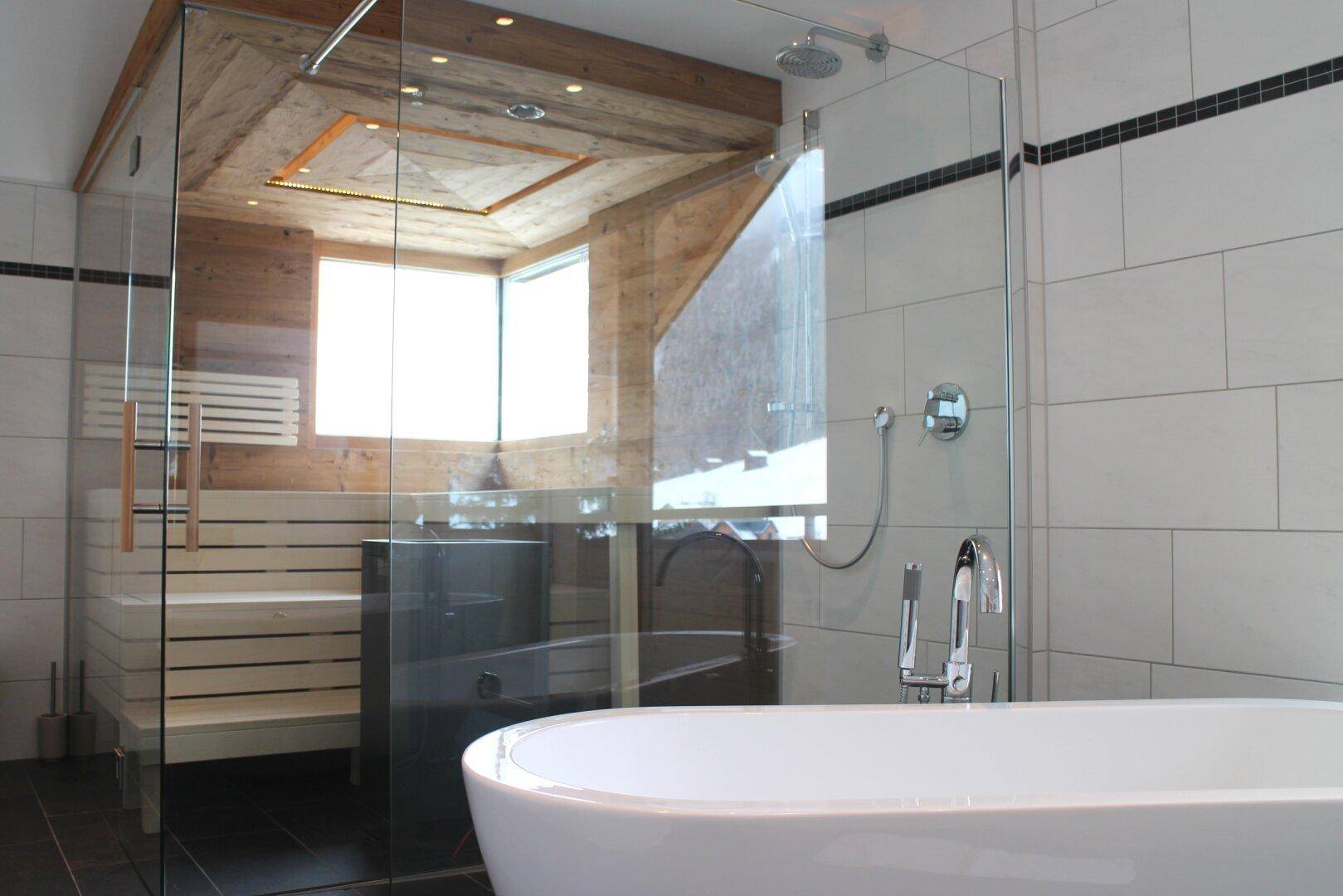 Luxuriöses Badezimmer mit freistehender Badewanne, Dusche und integrierter Sauna.