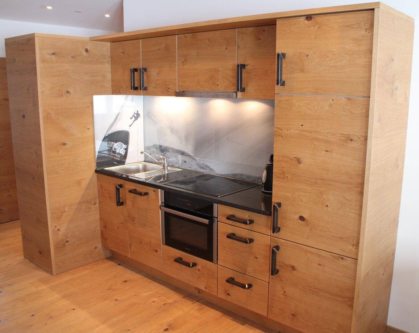 Moderne Holzküche mit integriertem Backofen, Kochfeld und viel Stauraum.