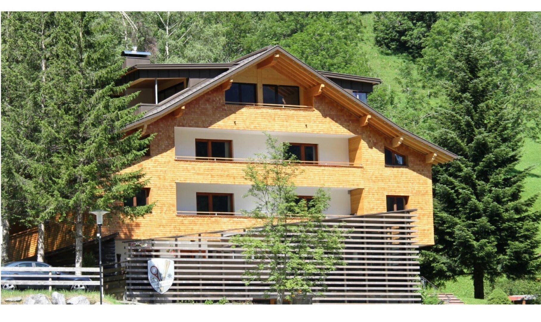 Charmantes Holzchalet in den Bergen, umgeben von grünen Bäumen und Natur.