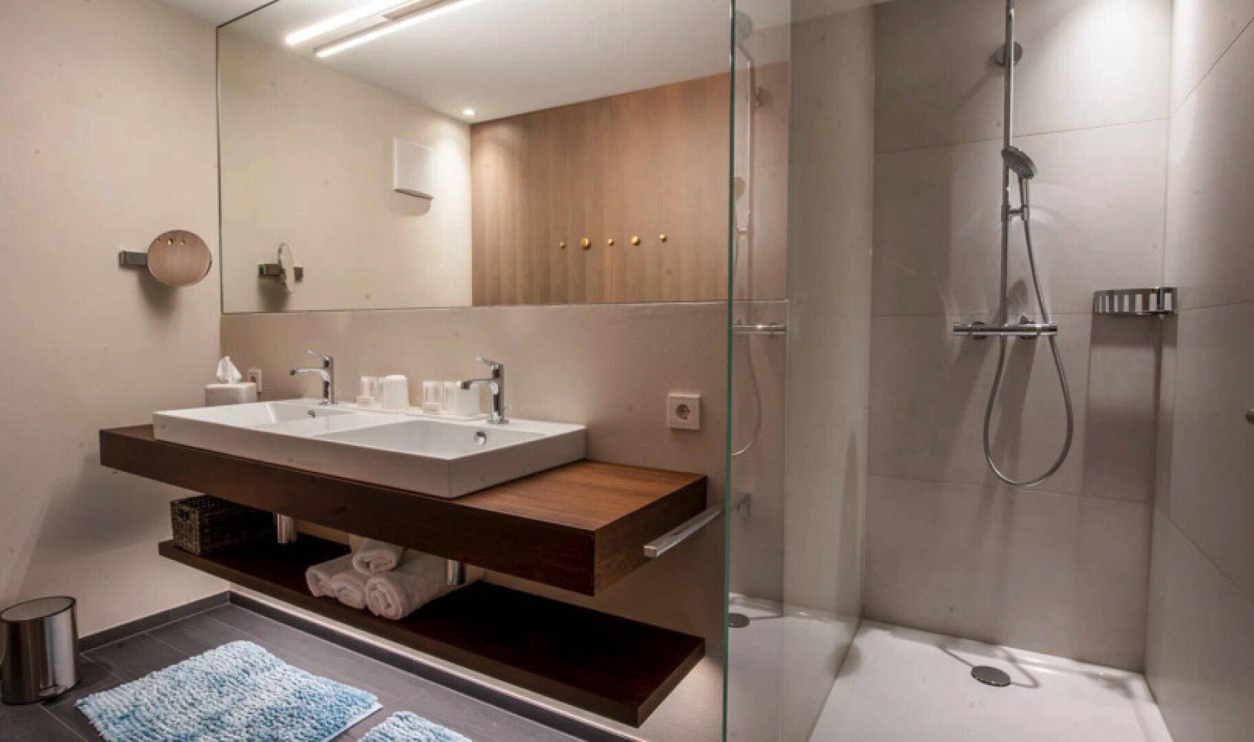 Modernes Badezimmer mit Doppelwaschbecken, schwebendem Waschtisch und großer Duschkabine.