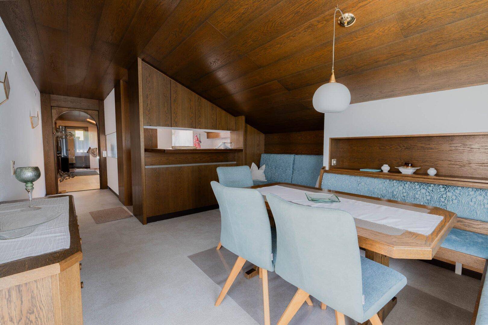 Rustikaler Essbereich mit Holzwänden und -decke, einem Esstisch und blauen Stühlen.