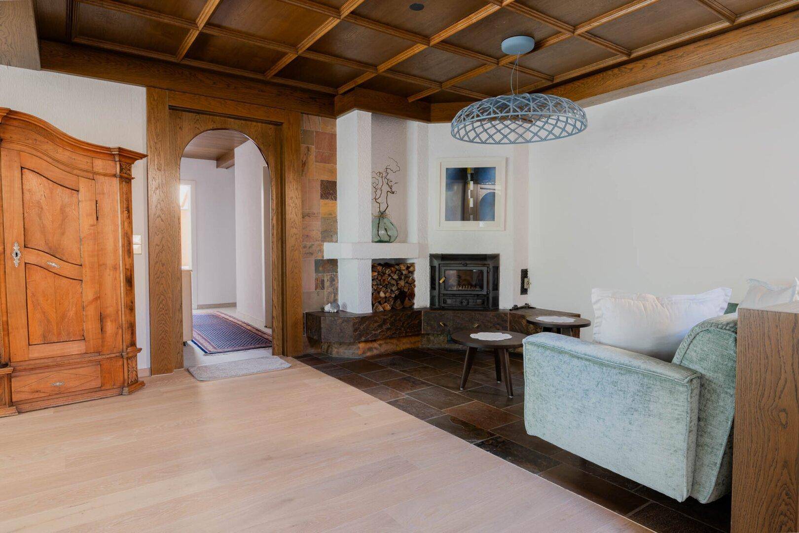 Gemütliches Wohnzimmer mit Kamin, Holzboden und traditioneller Kassettendecke.