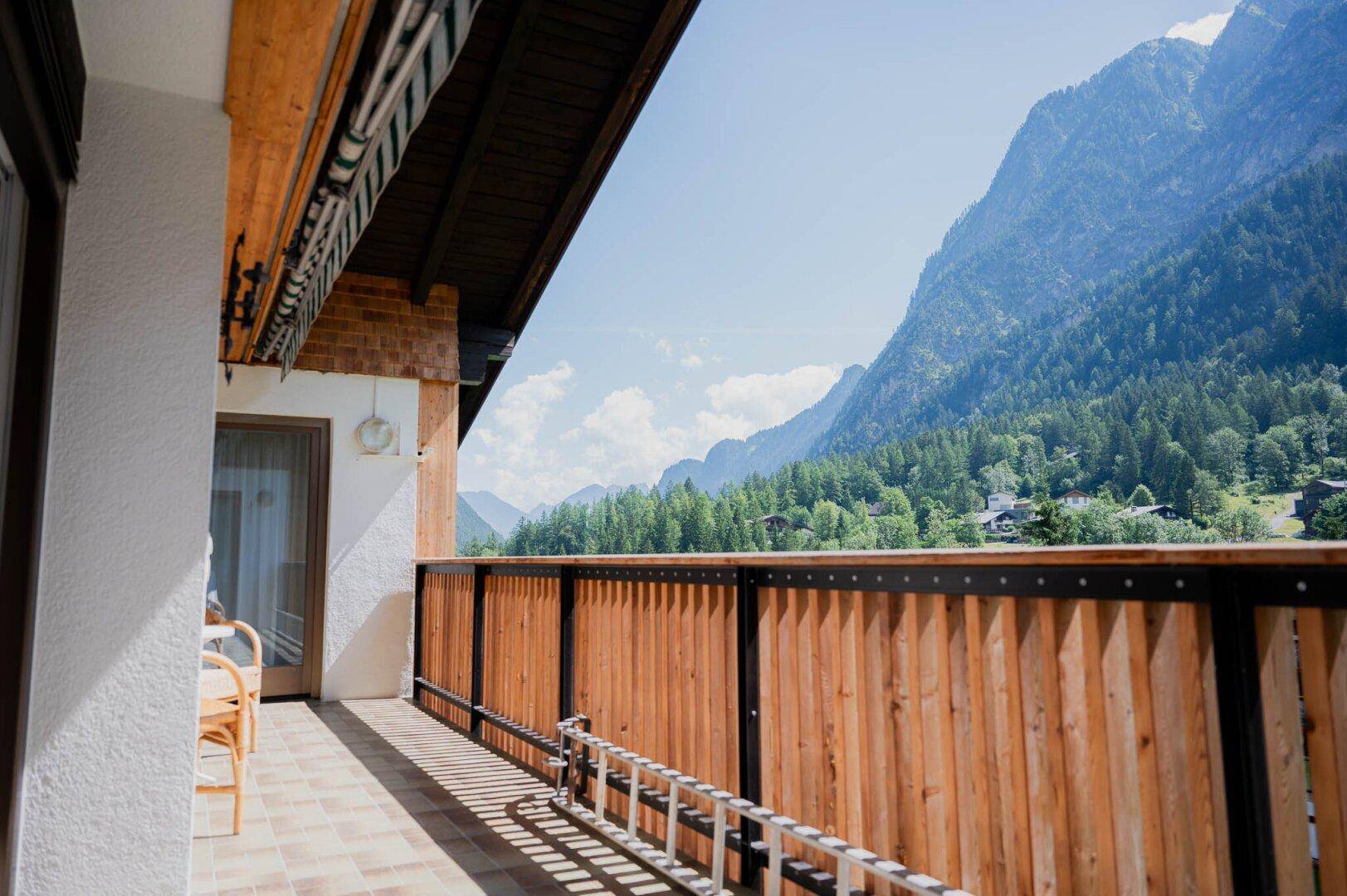 Großer Balkon mit Holzgeländer und atemberaubendem Blick auf die umliegenden Berge.