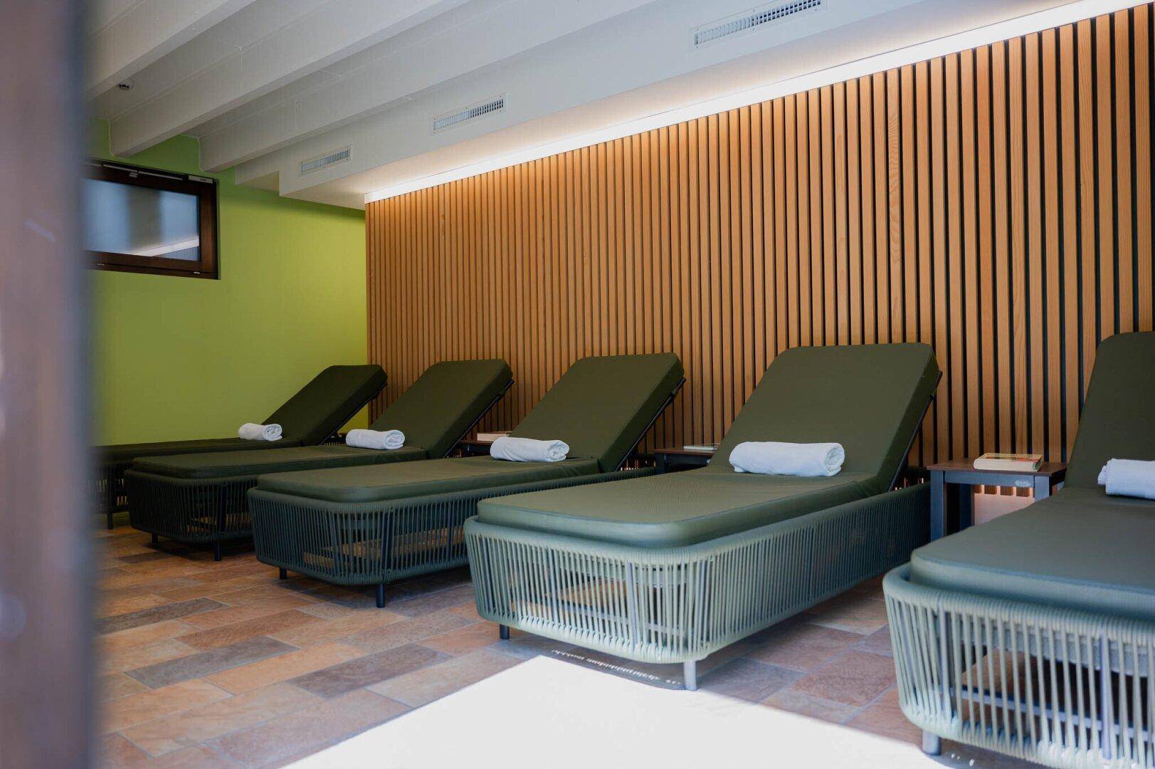 Ruhiger Ruheraum im Wellnessbereich mit bequemen Liegen und Holzverkleidung an der Wand.