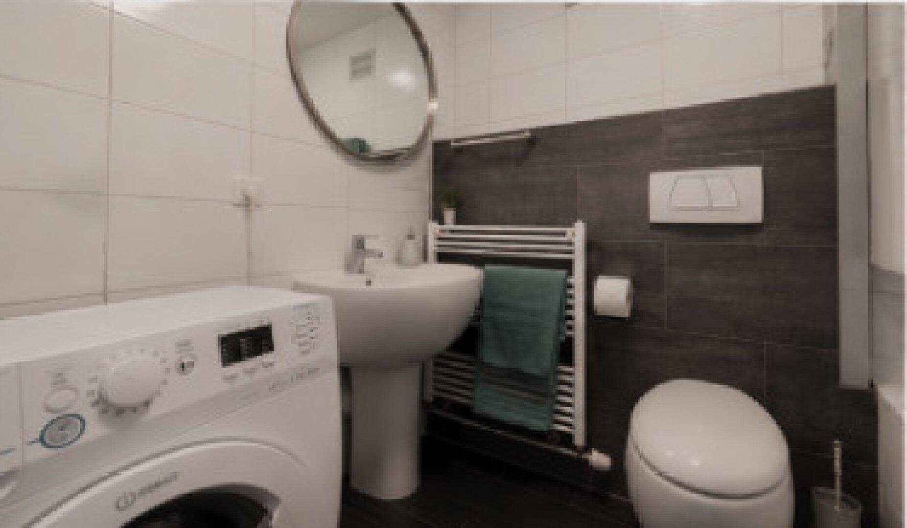 Modernes Badezimmer mit Waschbecken, Toilette, Waschmaschine und beheiztem Handtuchhalter.