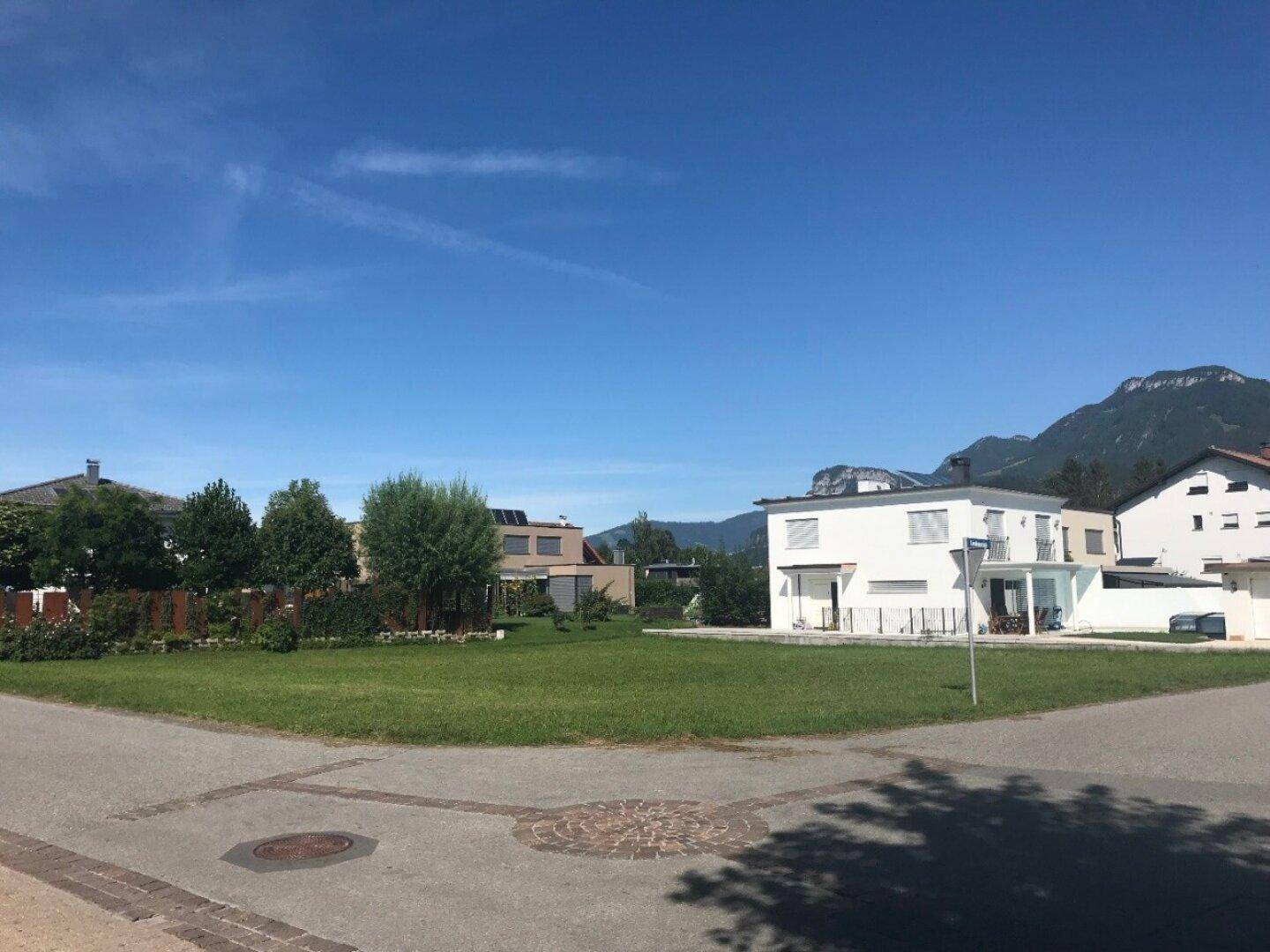 Wohngebiet mit Einfamilienhäusern, gepflegten Rasenflächen und Bergblick im Hintergrund.