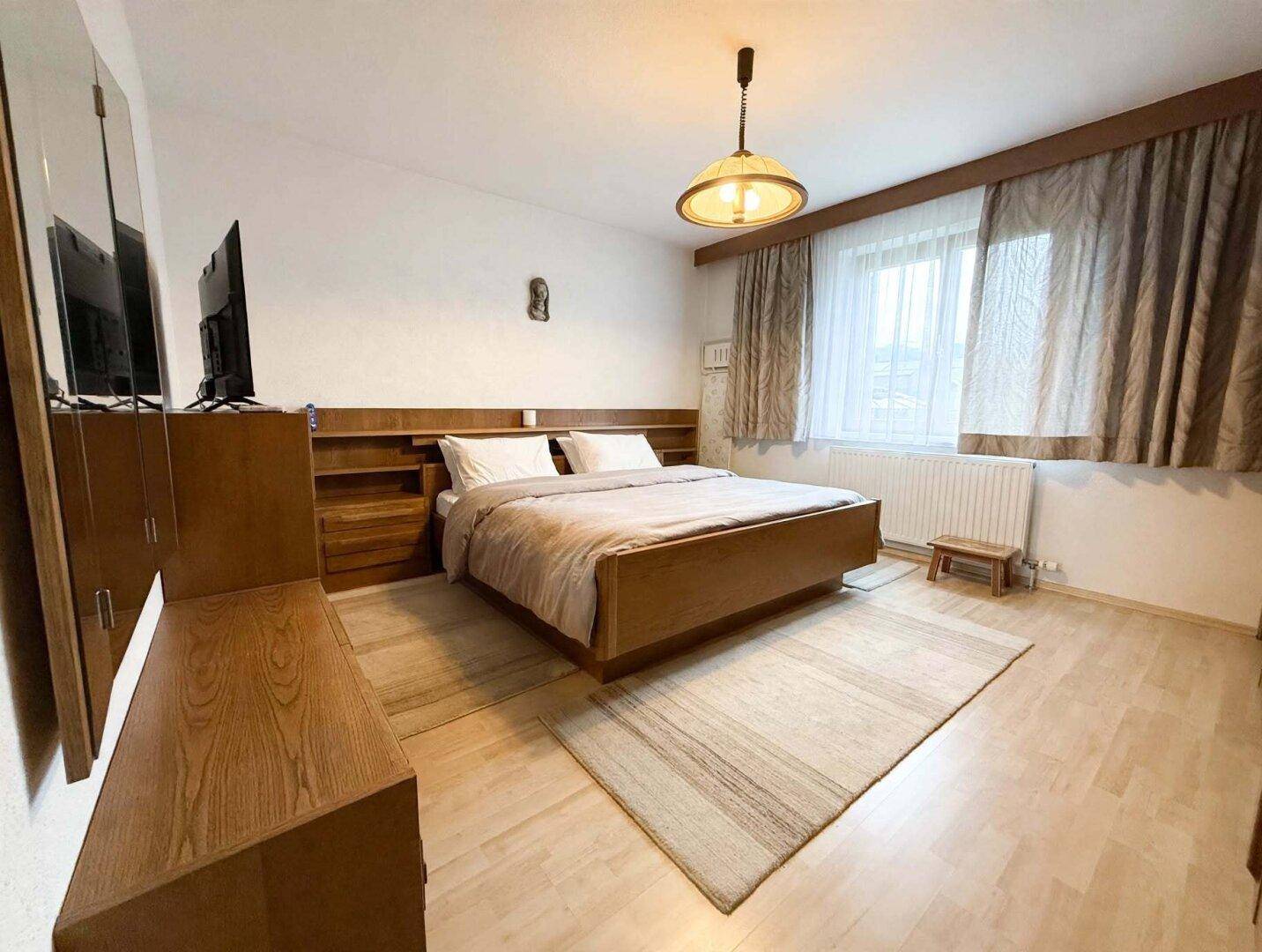 Gemütliches Schlafzimmer mit Holzmöbeln, hellem Holzboden und traditioneller Einrichtung, bietet eine warme Atmosphäre.