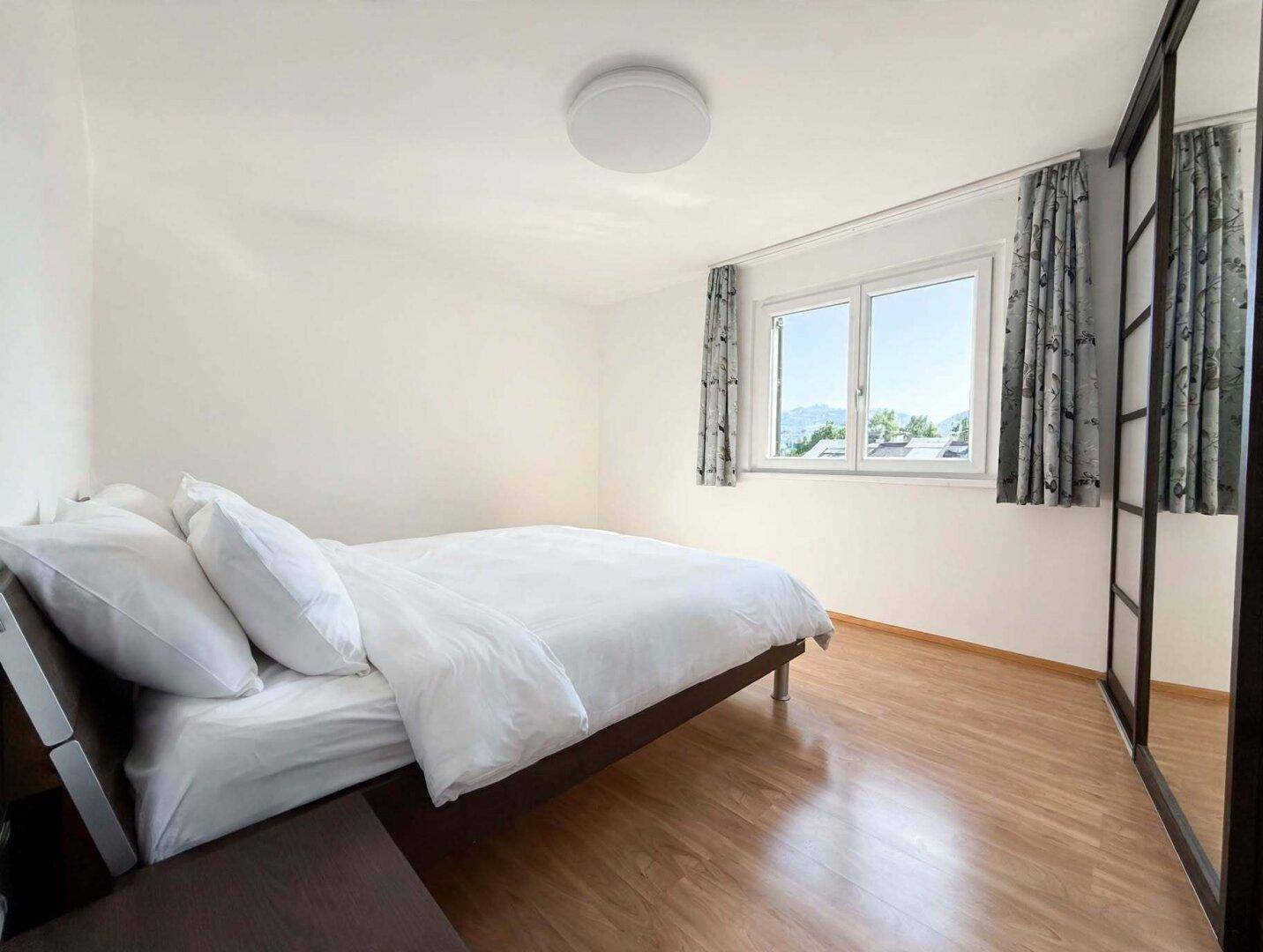 Schlafzimmer mit Doppelbett, Spiegelschrank und hellem Holzboden, bietet Komfort und Stauraum.