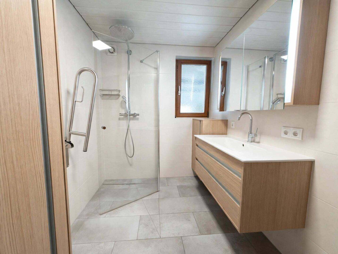 Modernes Badezimmer mit ebenerdiger Dusche, Einzelwaschbecken und Haltegriffen für Komfort.