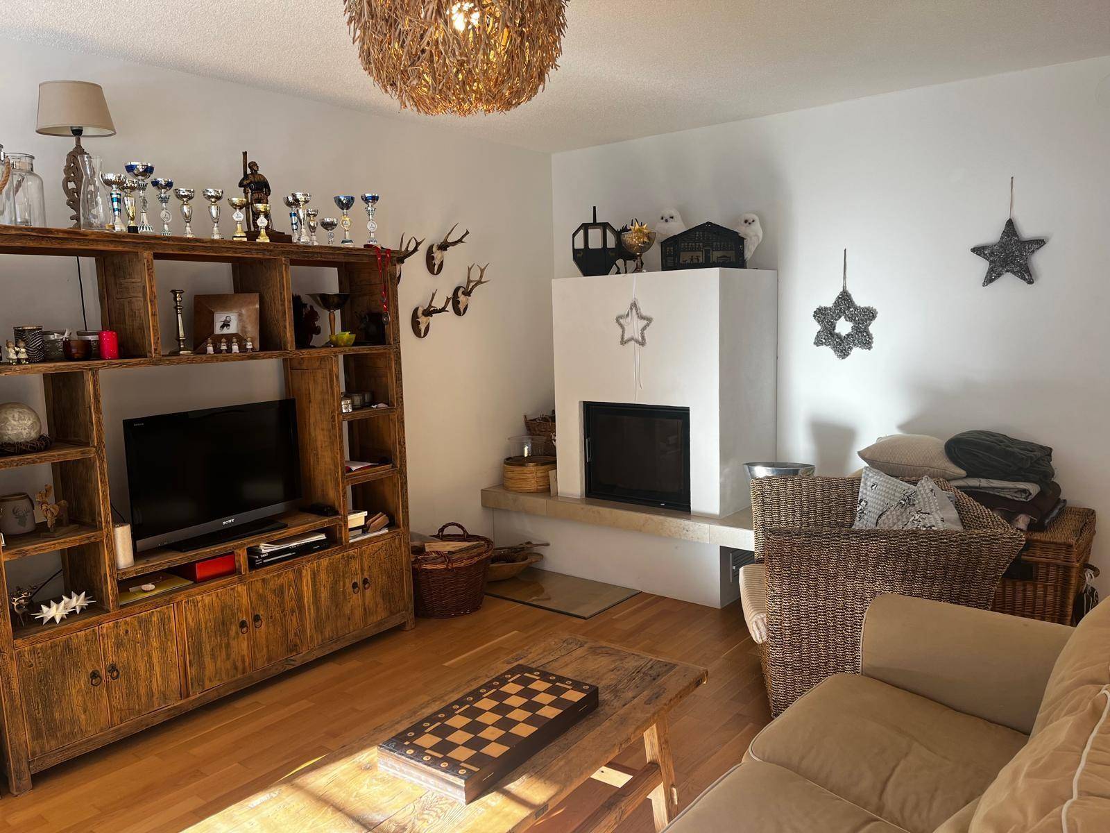 Gemütliches Wohnzimmer mit Kamin, rustikalen Holzmöbeln und alpiner Dekoration.