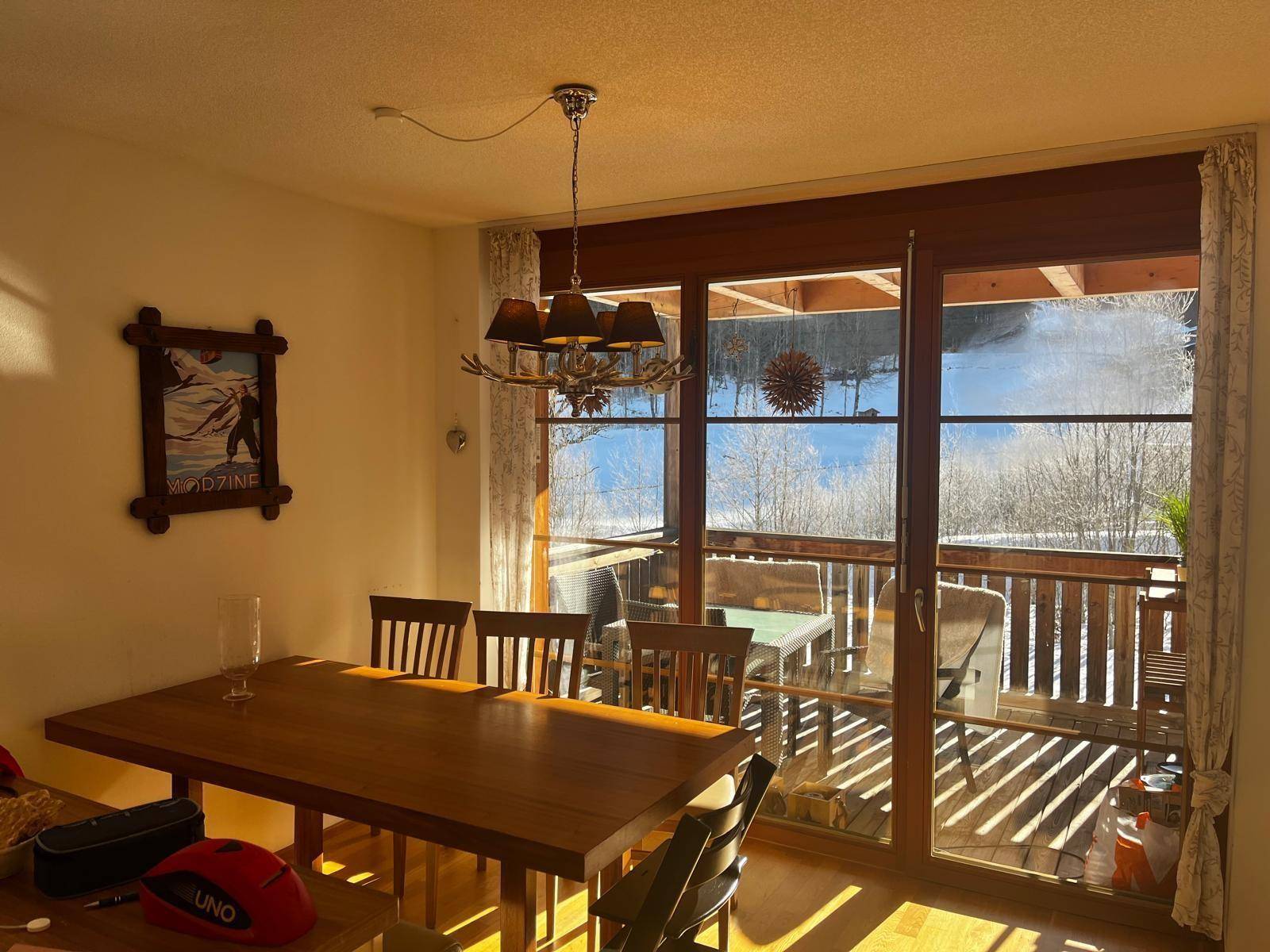 Heller Essbereich mit Holztisch und direktem Zugang zu einem sonnigen Balkon mit Bergblick.
