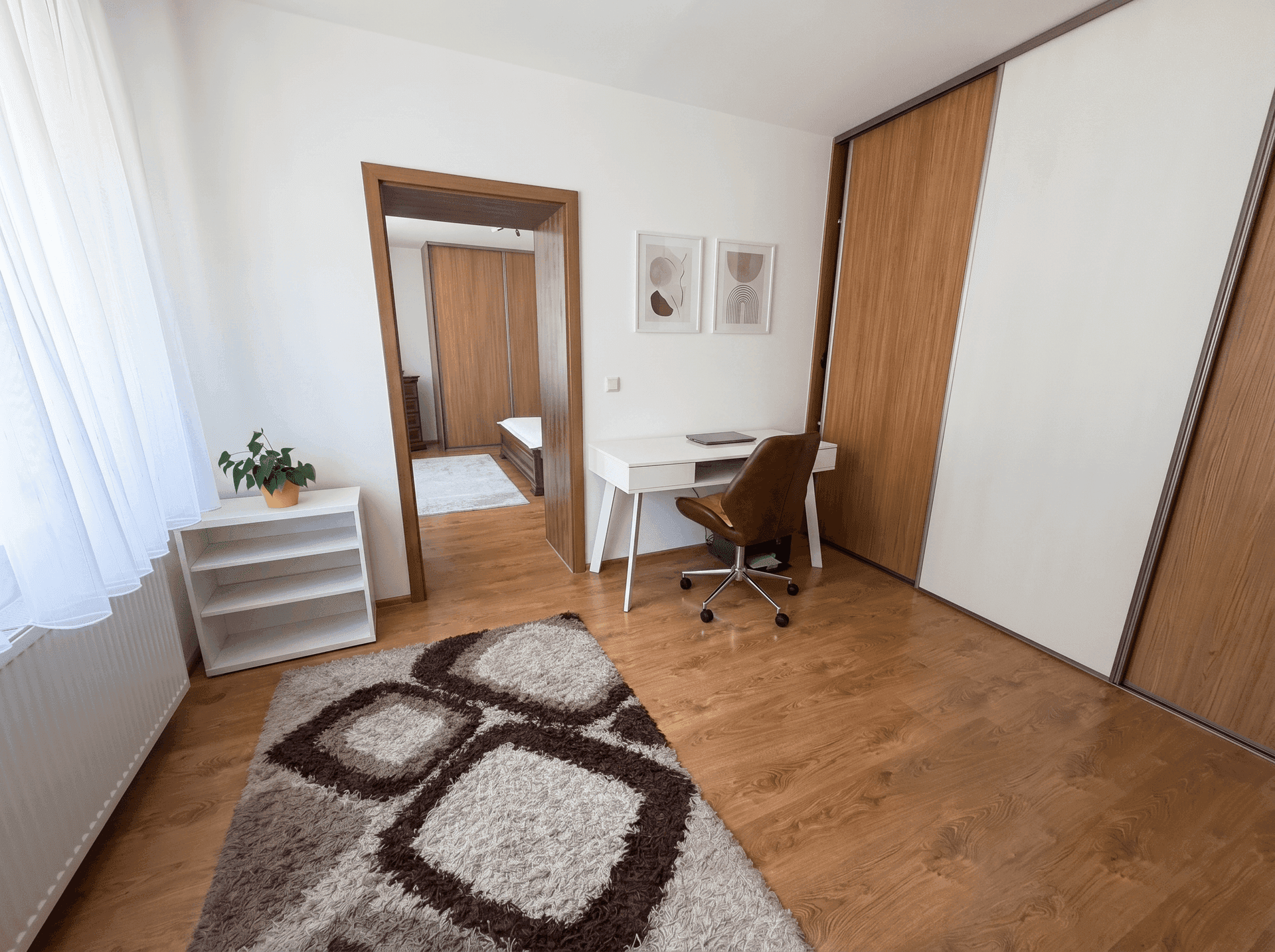 Funktionales Arbeitszimmer mit Schreibtisch, Holzboden und Einbauschränken.