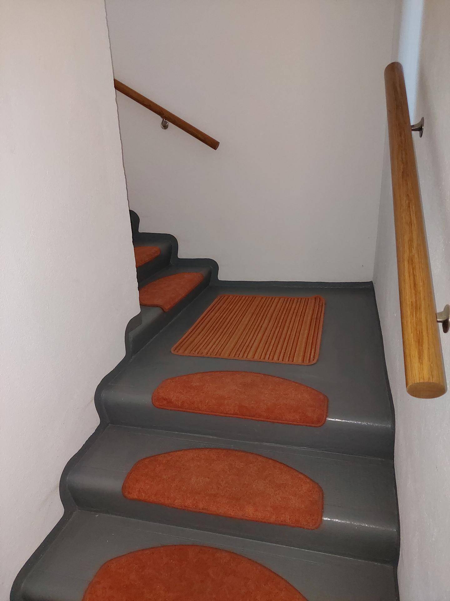 Treppenhaus mit Holzgeländer und Teppichstufen, führt in die oberen Etagen.