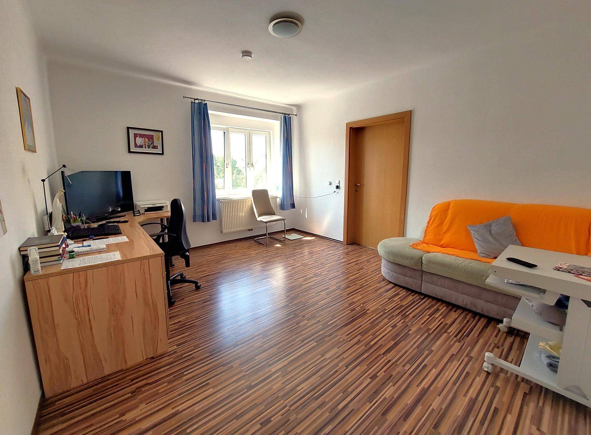 Helles Arbeitszimmer mit Schreibtisch, Bürostuhl und einem Sofa, ideal für Home-Office.