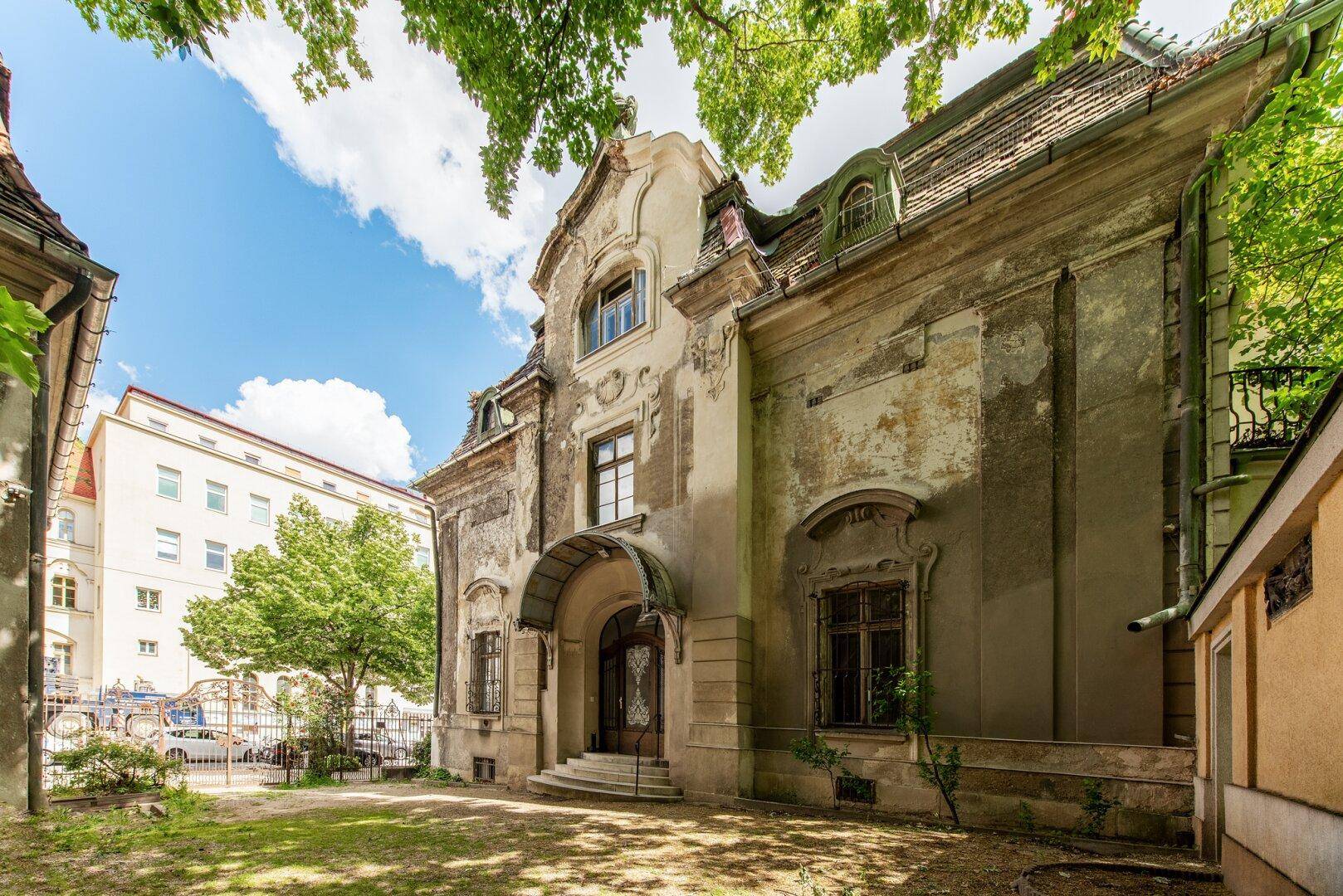 Verwitterte Fassade eines historischen Gebäudes mit architektonischen Details und altem Charme.