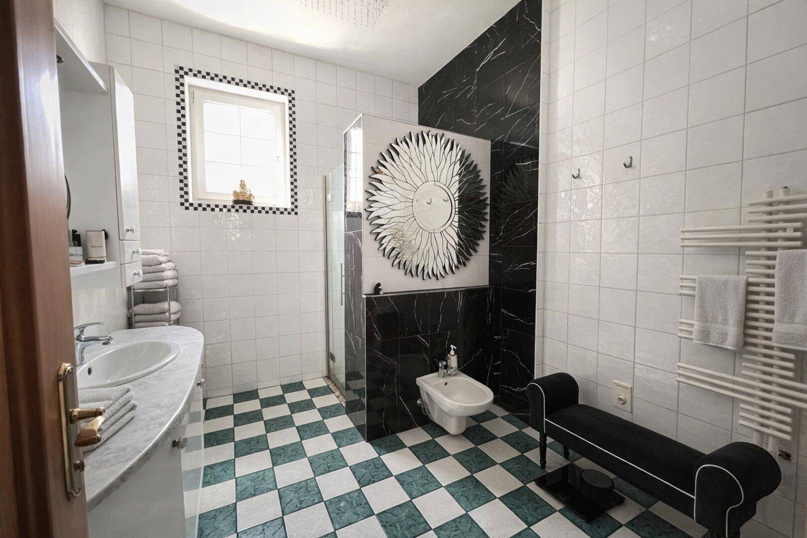 Modernes Badezimmer mit schwarz-weißem Fliesenmuster, Doppelwaschbecken und Bidet.
