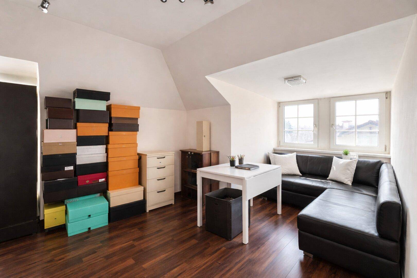 Helles Dachgeschosszimmer als Büro genutzt, mit Schrägdach und Holzboden.