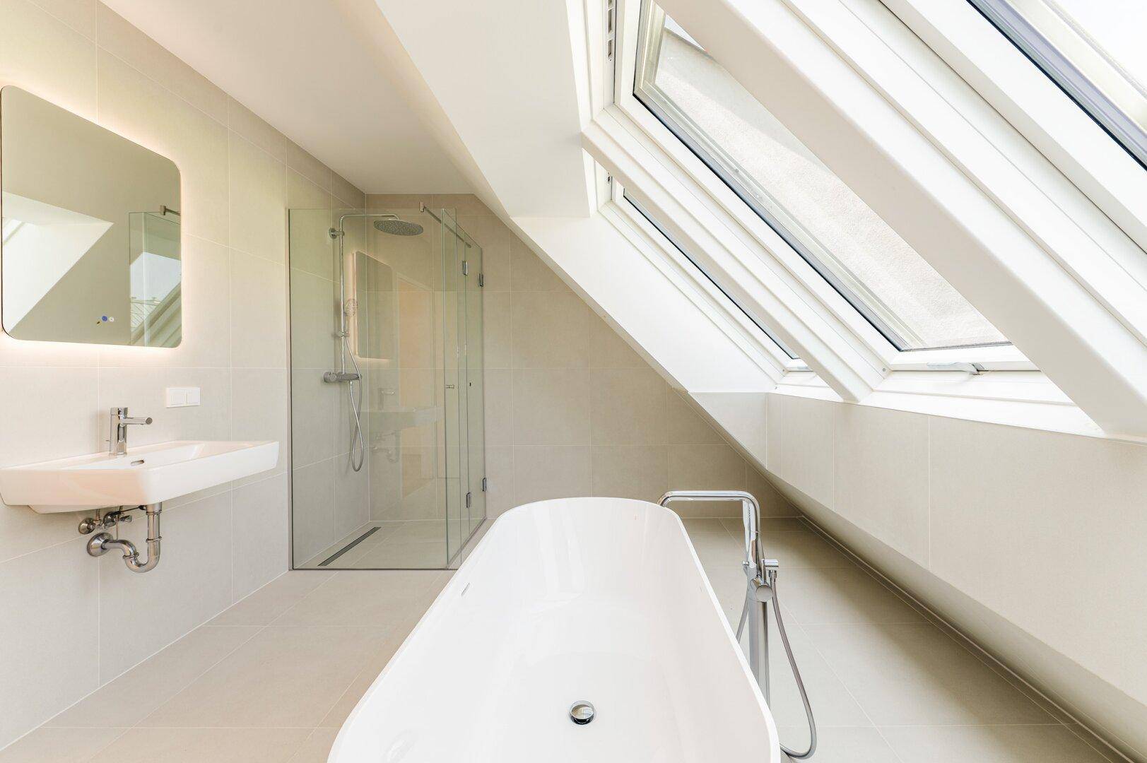 Modernes Badezimmer mit freistehender Badewanne, begehbarer Dusche und großen Dachfenstern.