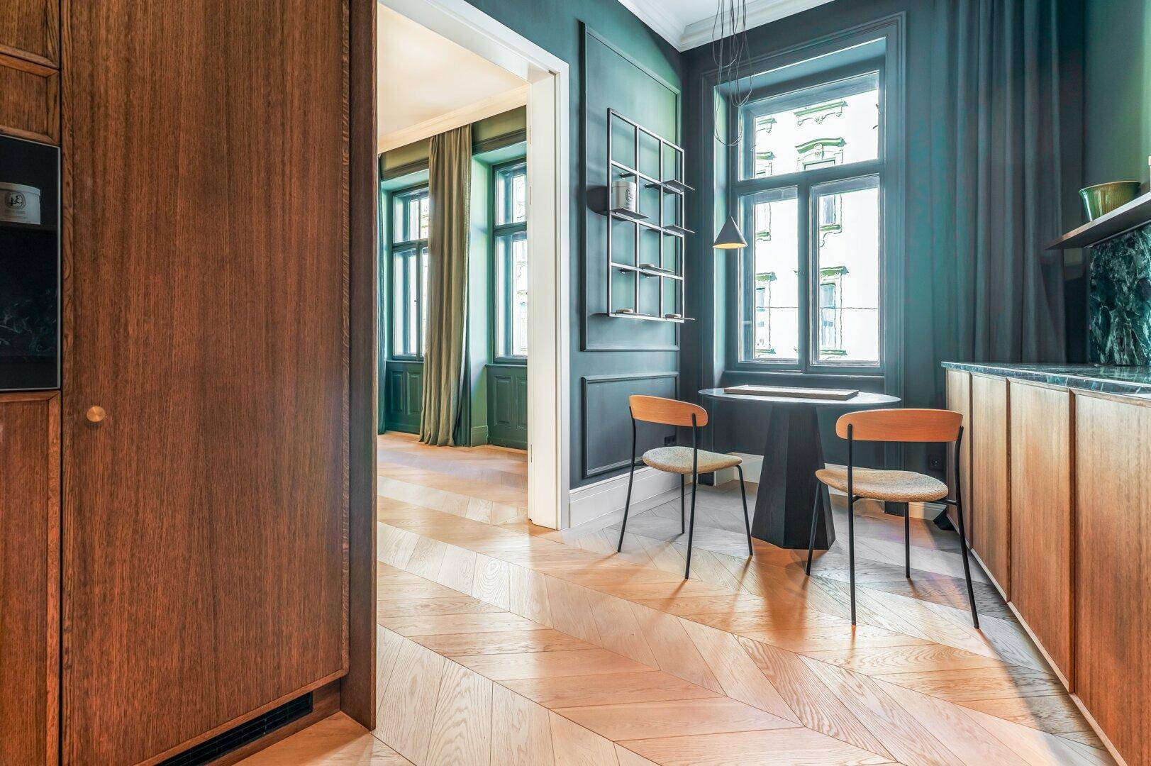 Elegante Diele mit dunklen Holzeinbauten und Blick in ein weiteres Zimmer mit Fischgrätparkett.