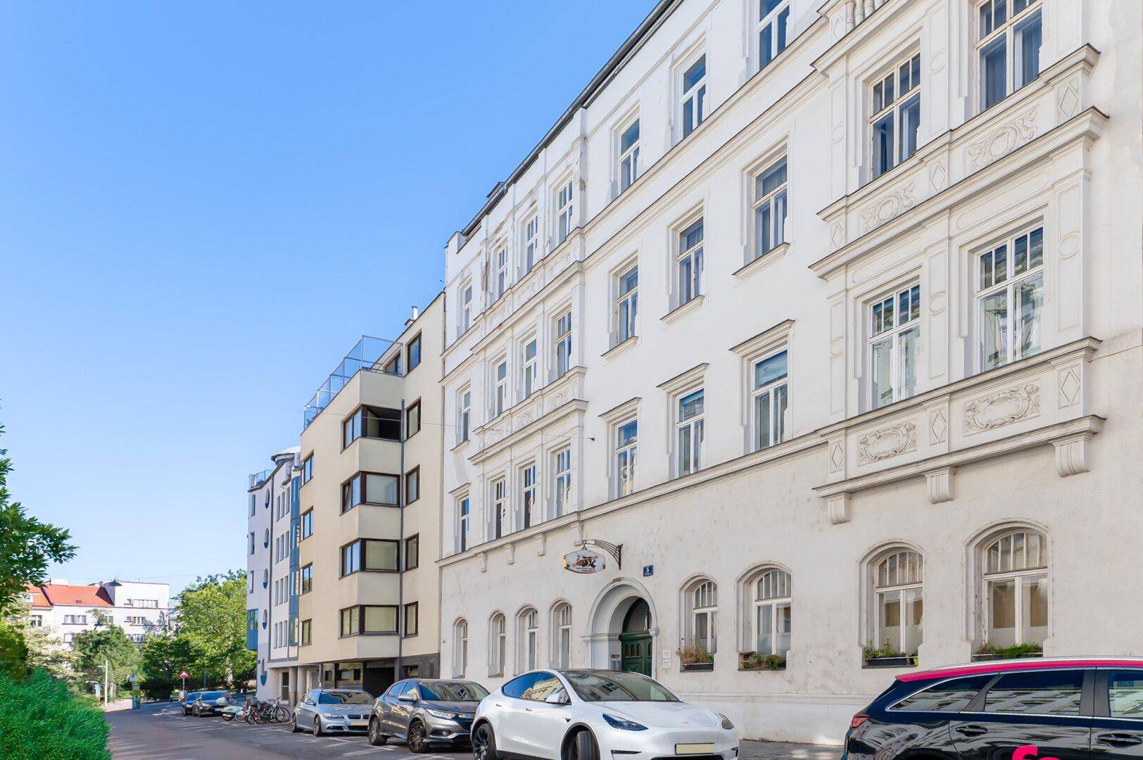 Historisches Wohngebäude mit moderner Architektur im Hintergrund an einer städtischen Straße.