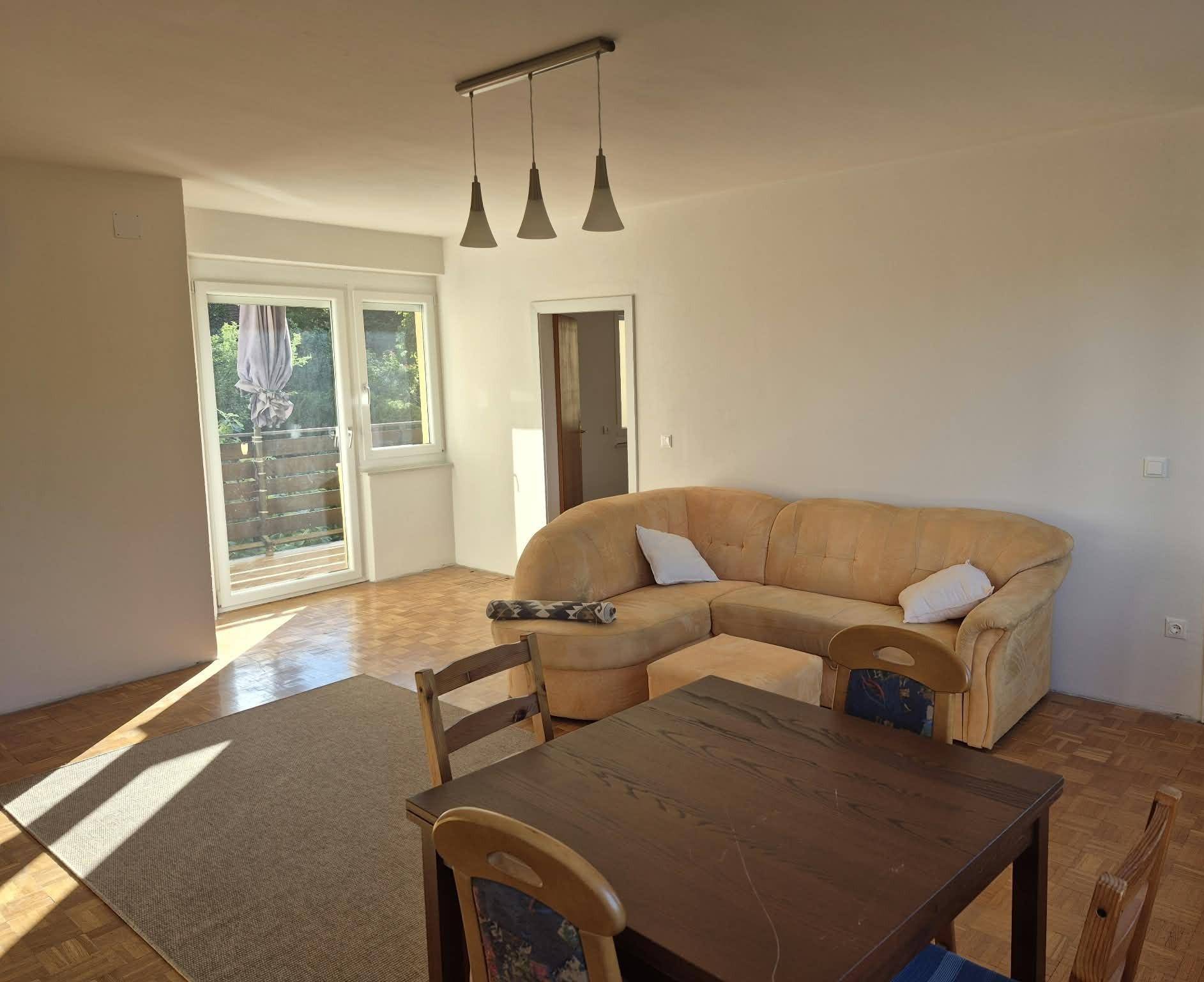 Heller Wohn-Essbereich mit Sofa, Esstisch und direktem Zugang zu einem sonnigen Außenbereich.