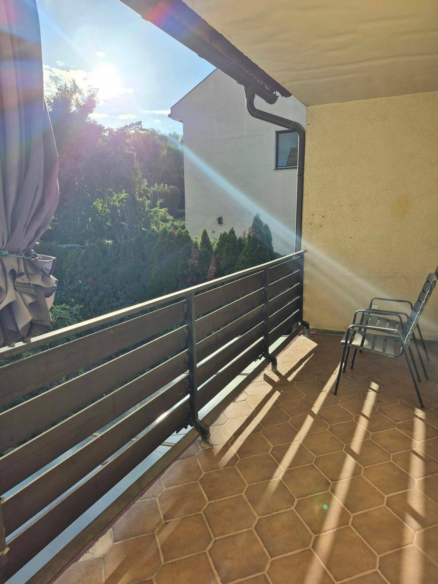 Heller Balkon mit Terrakotta-Fliesen, stabiler Brüstung und Sitzgelegenheiten, ideal für sonnige Tage.
