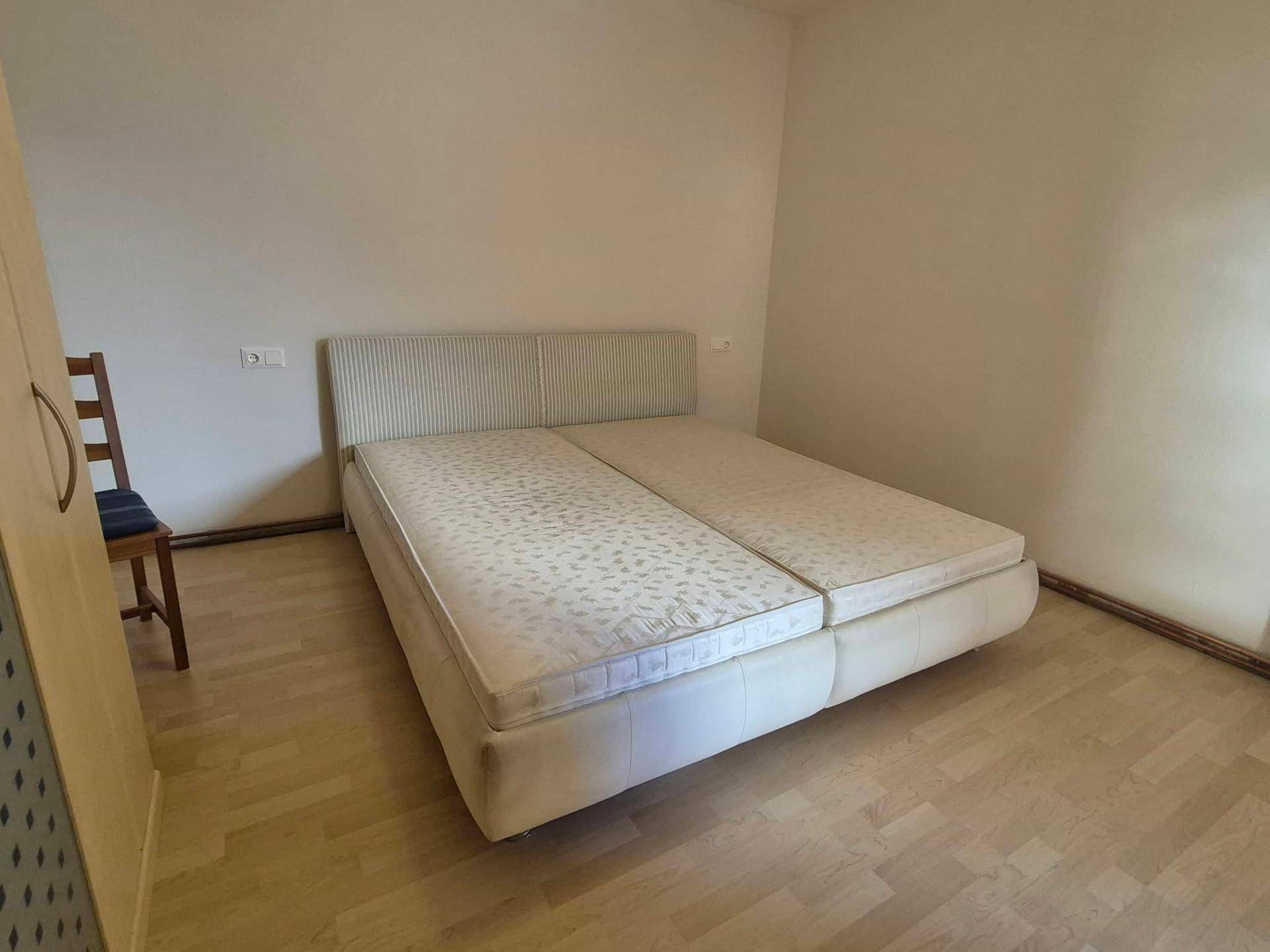 Helles Schlafzimmer mit einem Doppelbett und klassischem Parkettboden, in gutem Zustand.