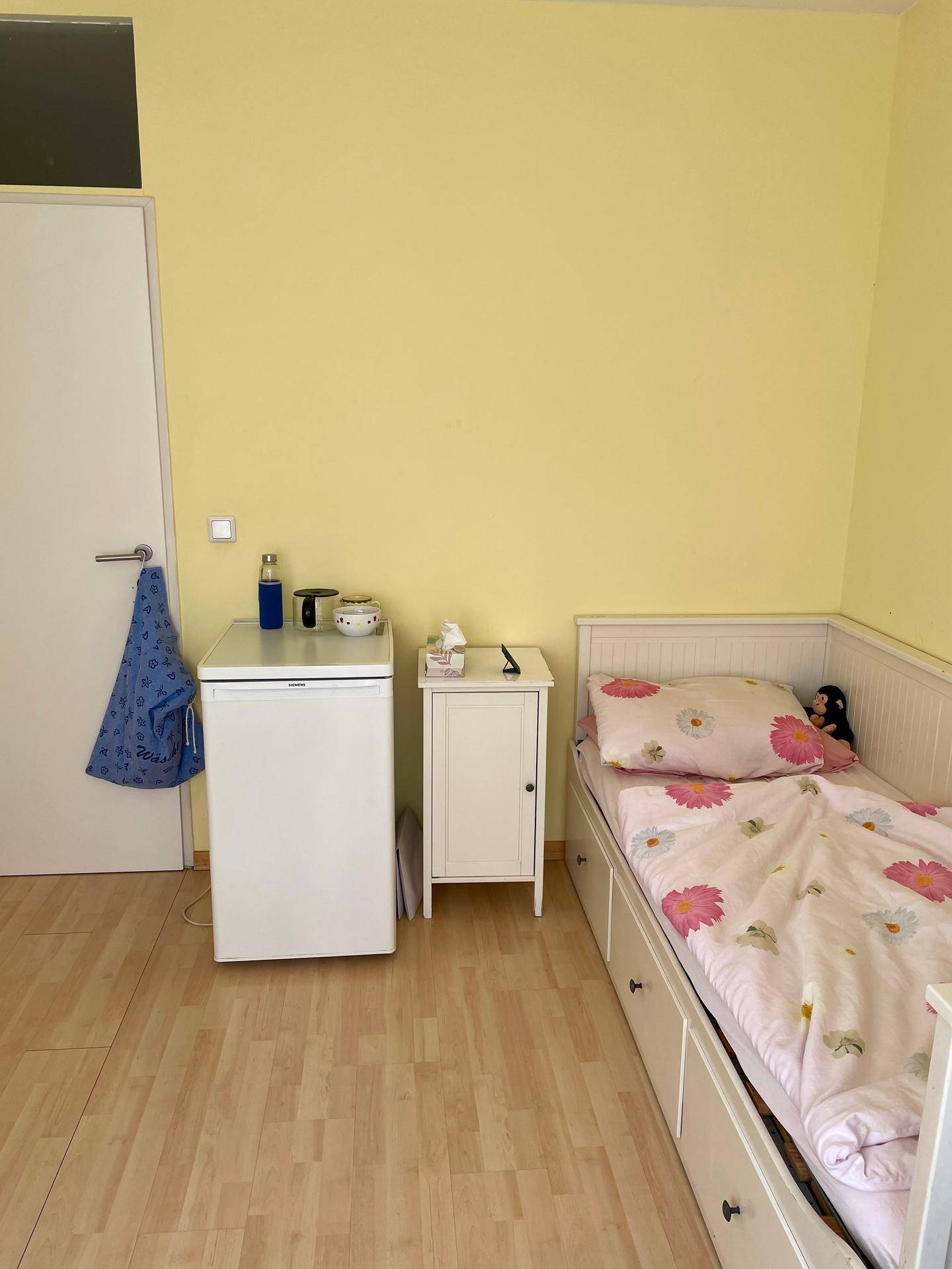 Gemütliches Schlafzimmer mit Einzelbett, Nachttisch und einem kleinen Kühlschrank.