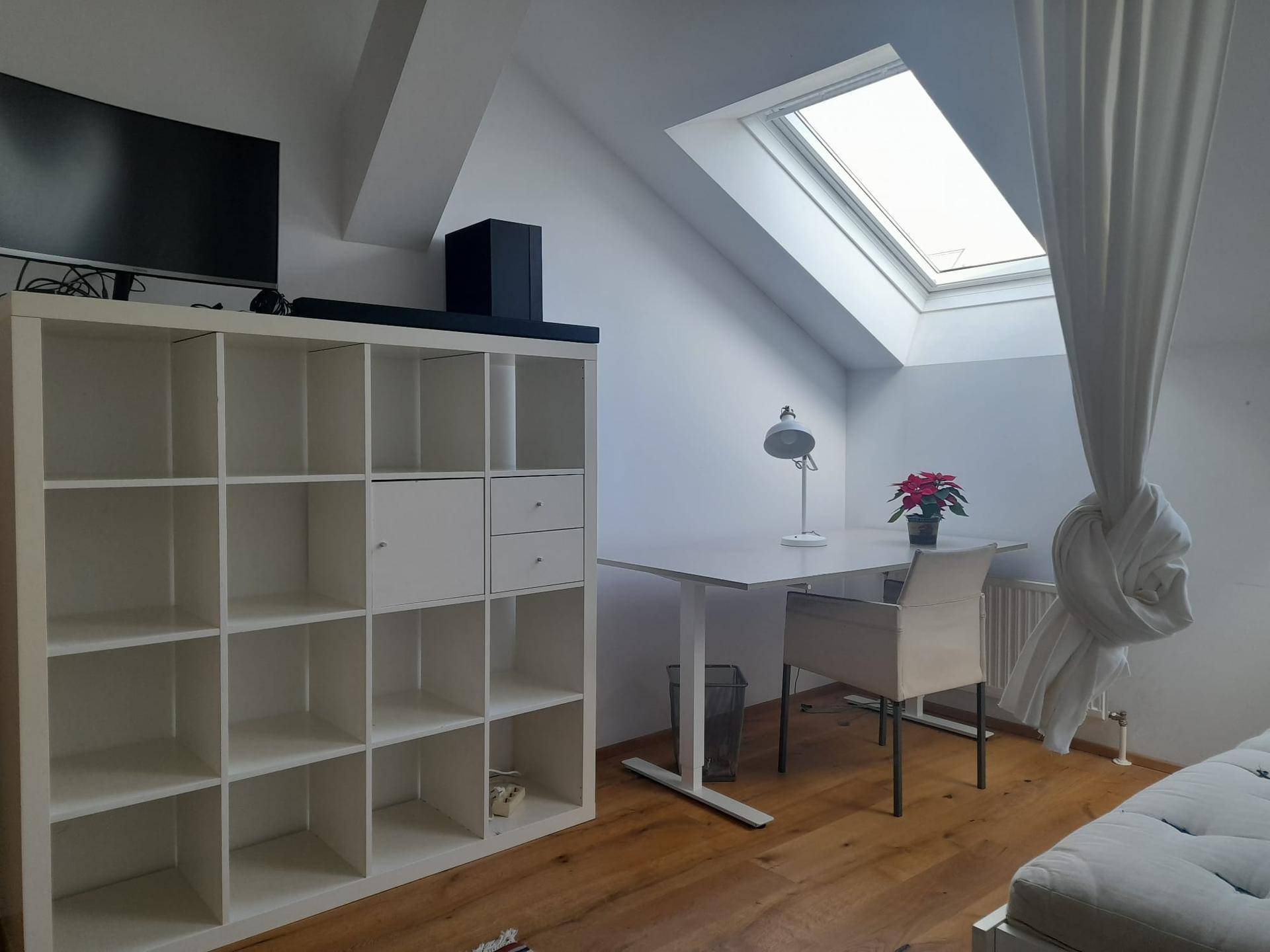 Arbeitsbereich im Dachgeschoss-Schlafzimmer mit Schreibtisch, Regal und viel Tageslicht durch das Dachfenster.