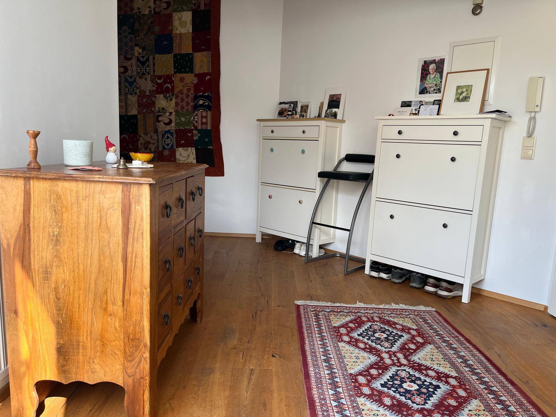 Eingangsbereich mit Holzboden, rustikaler Kommode, Schuhschränken und einem gemusterten Teppich.