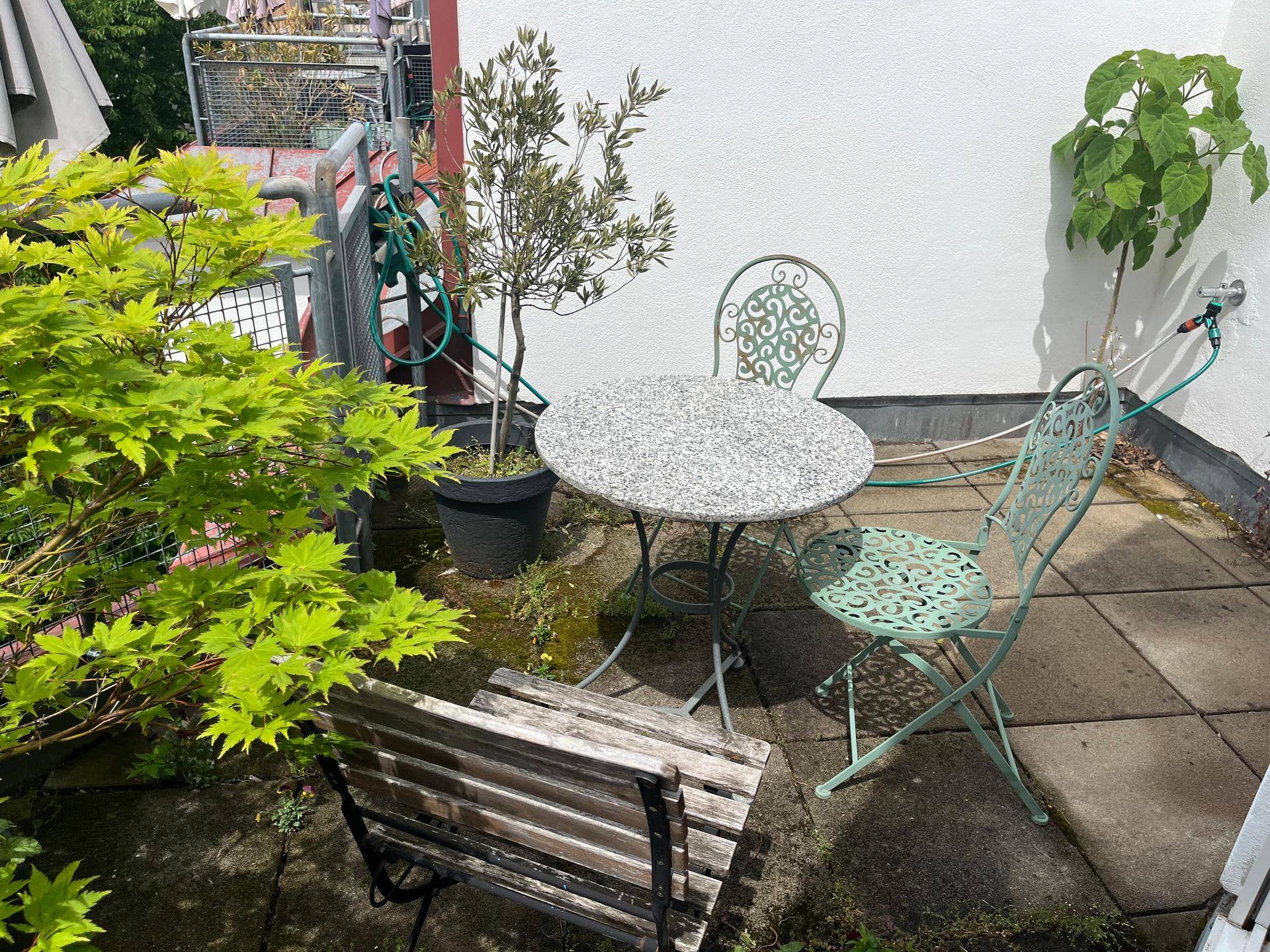 Kleine Terrasse mit Gartentisch, Stühlen und Topfpflanzen, ideal für entspannte Stunden im Freien.