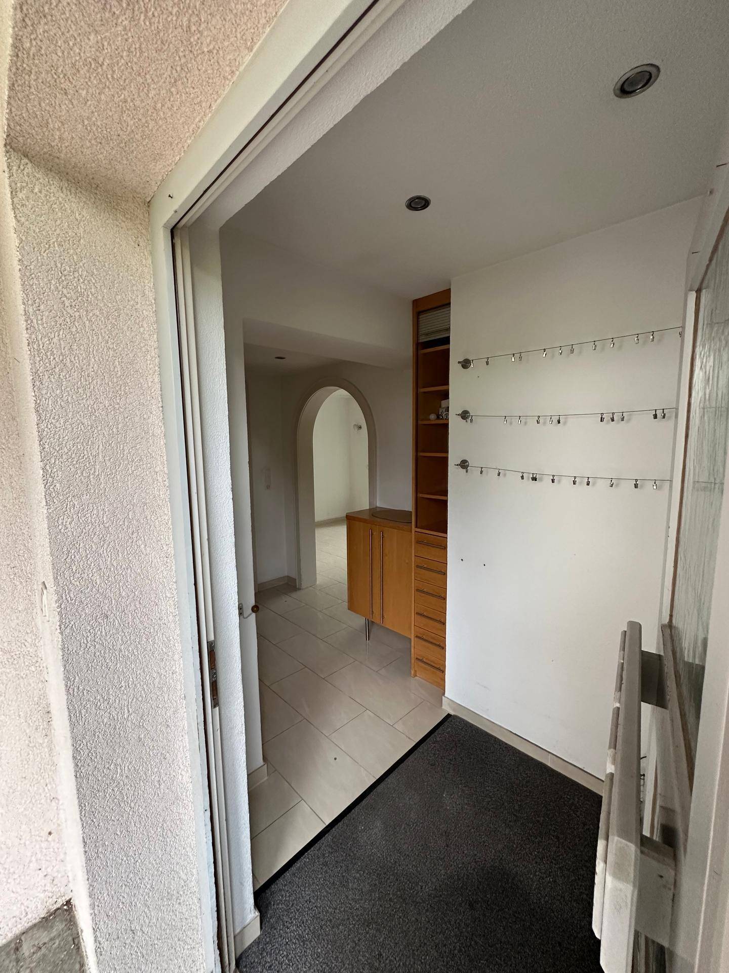 Eingangsbereich mit Fliesenboden, Garderobe und Blick in den Wohnbereich.