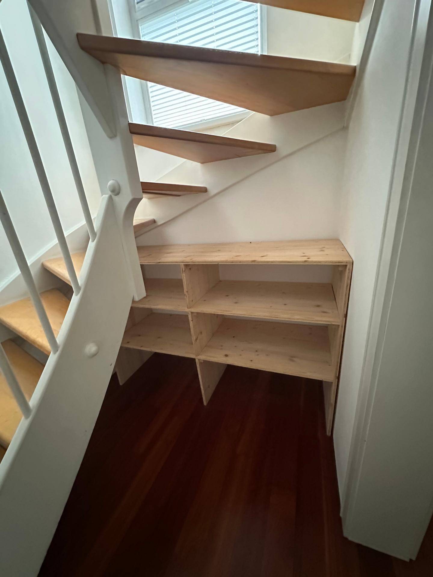Praktischer Stauraum unter der Treppe mit Holzregalen für zusätzlichen Platz.